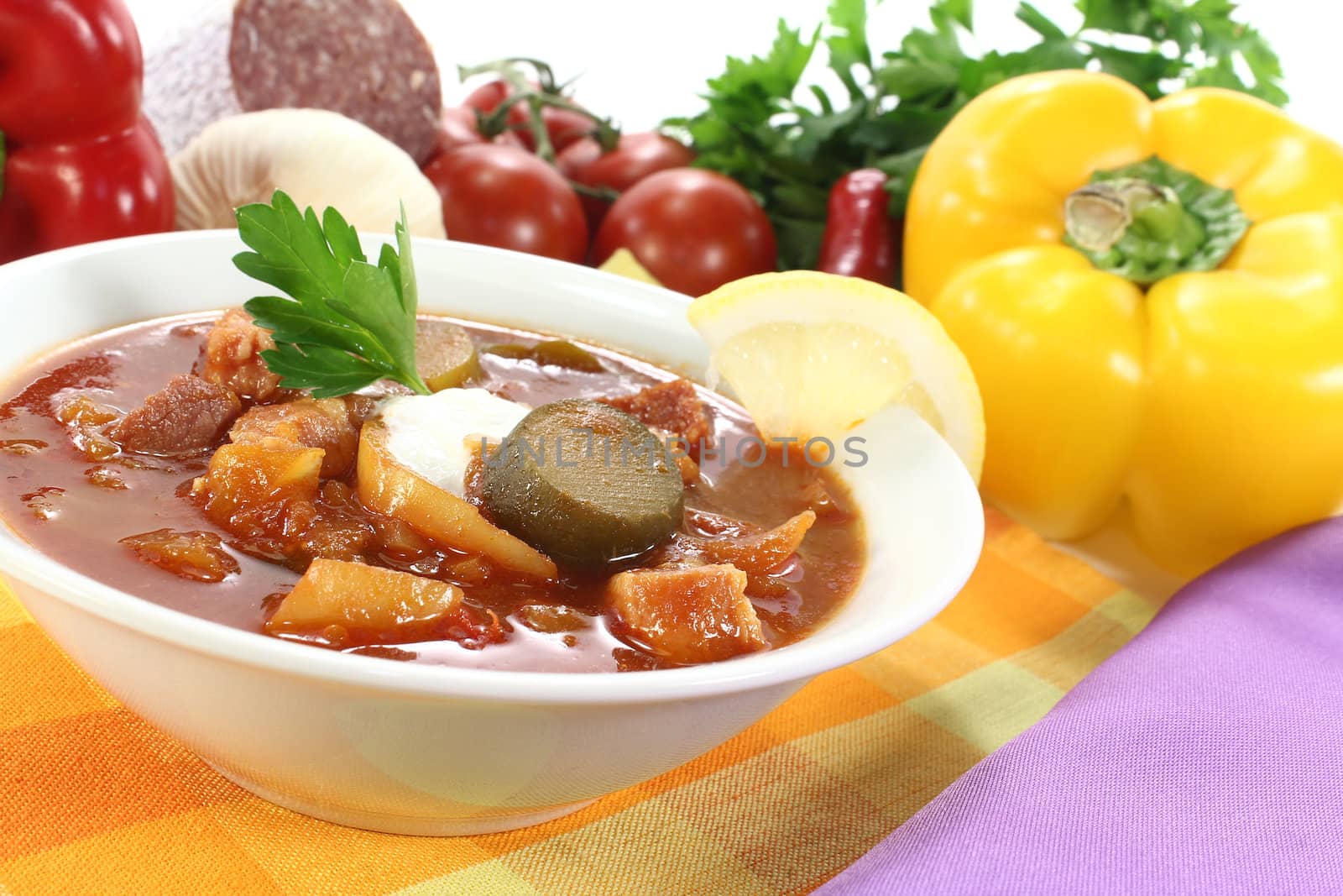 Solyanka with cream, parsley and lemon on a light background