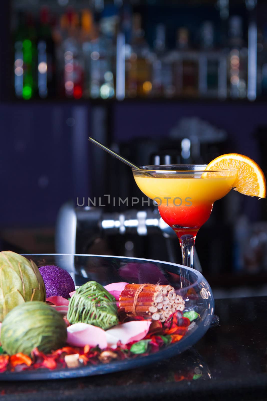 Orange cocktail with a straw on the bar