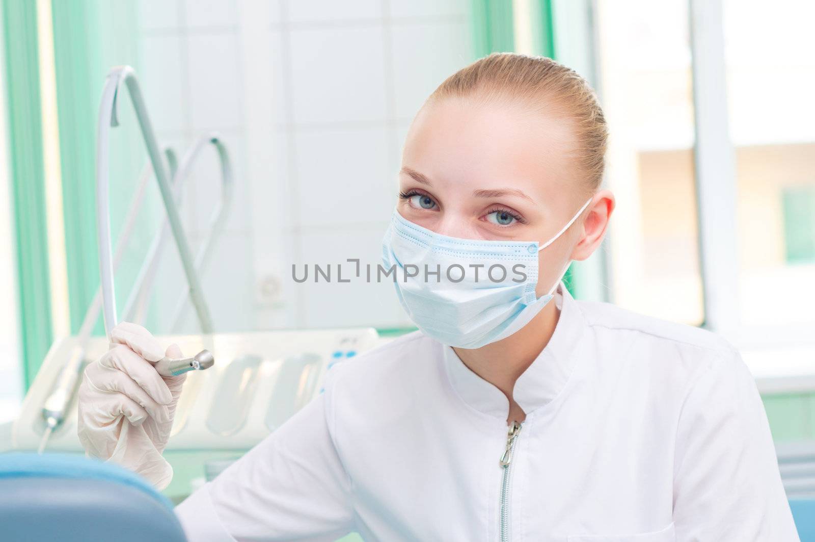female dentists in protective mask holds a dental drill, the doctors at work