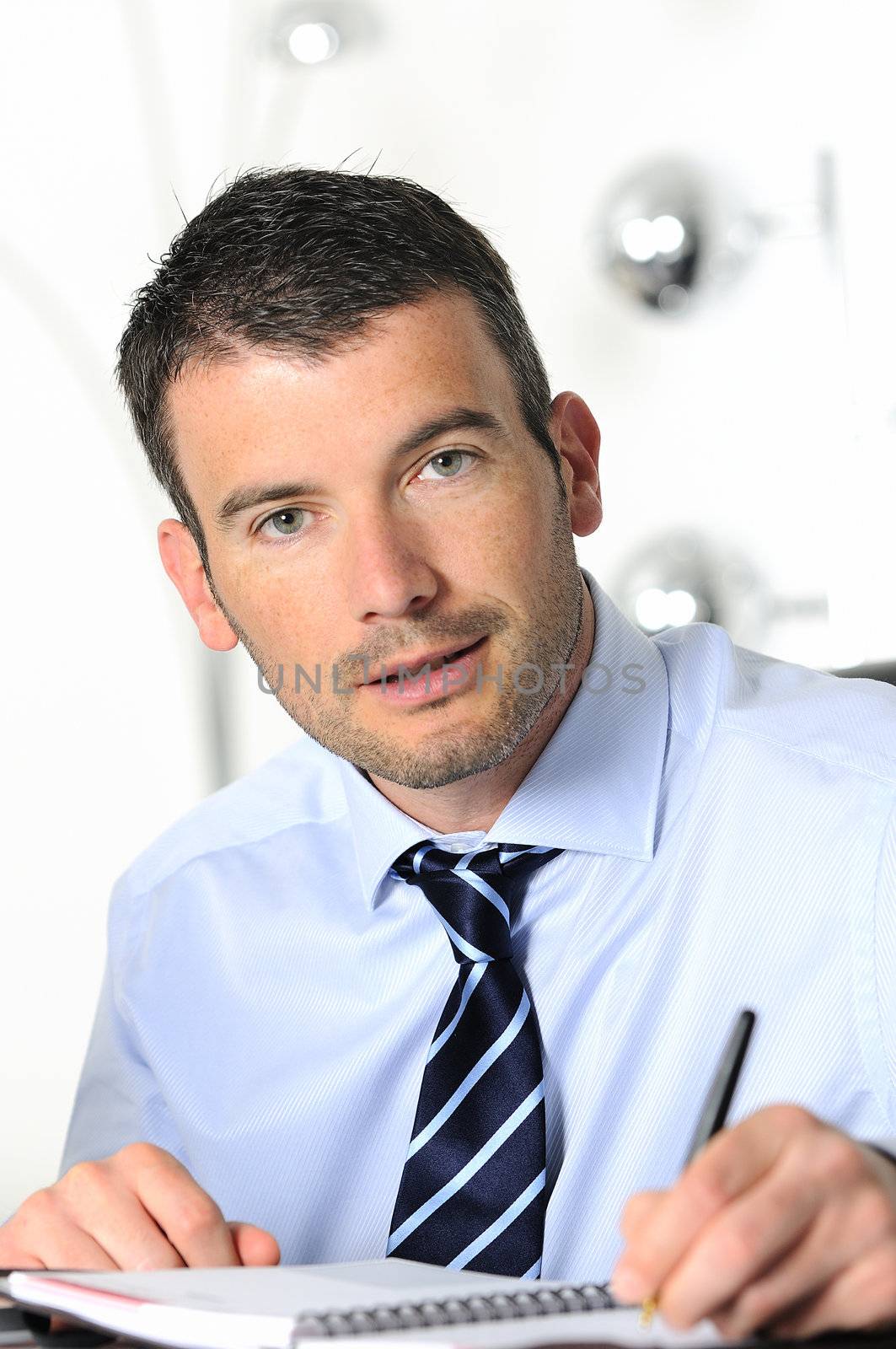 An attractive business man is writing on a paper