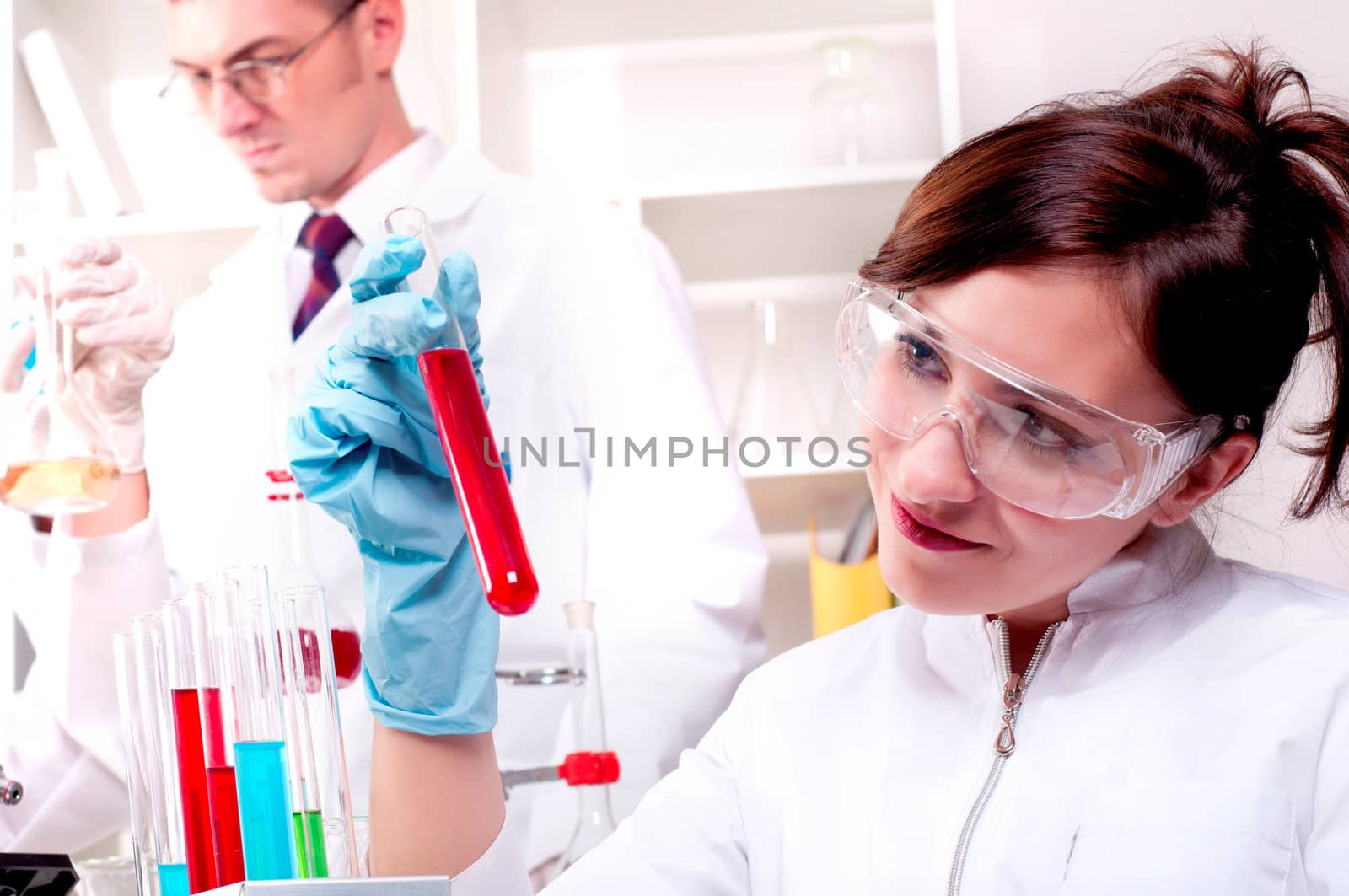 portrait of a beautiful woman chemist, looks at a test tube with red fluid