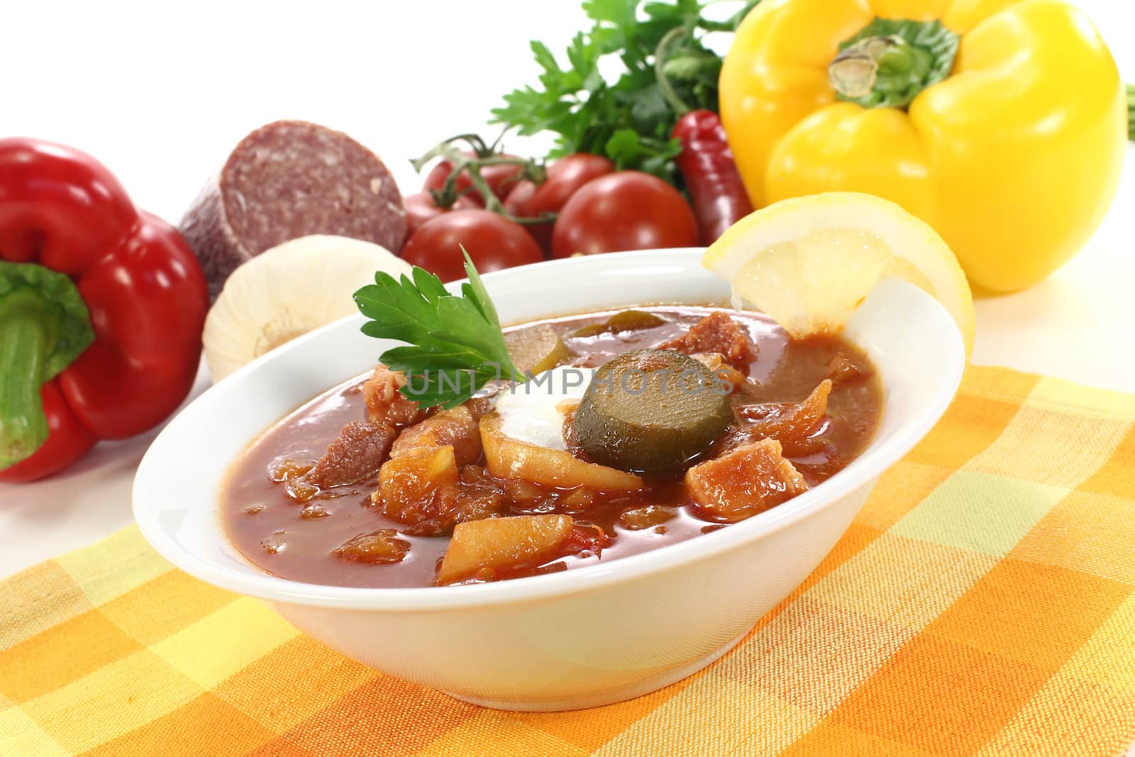 delicious Solyanka with cream, parsley and lemon on a light background