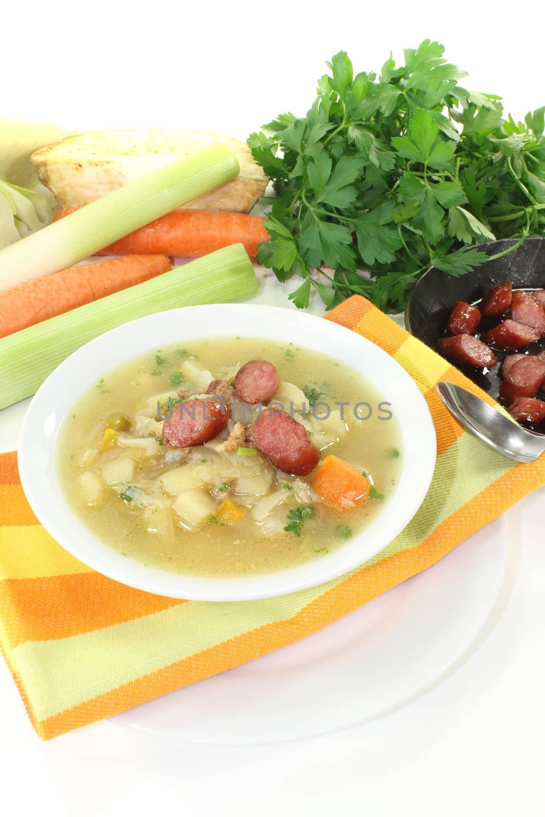 white cabbage soup with vegetables and fried sausage on a light background