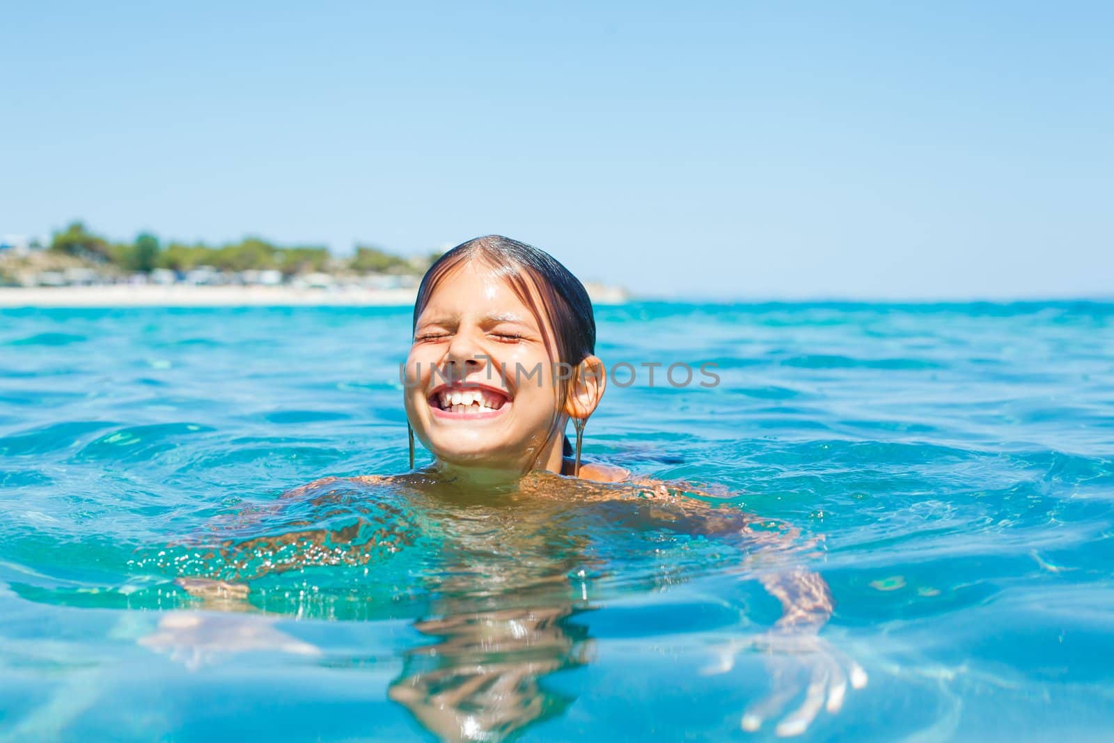 Young girl playing and swimming in the transparent sea