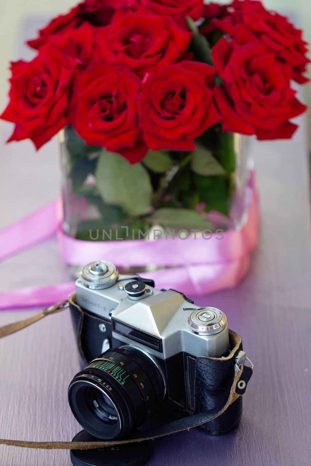 Bouquet of red roses and old camera. day Photographer