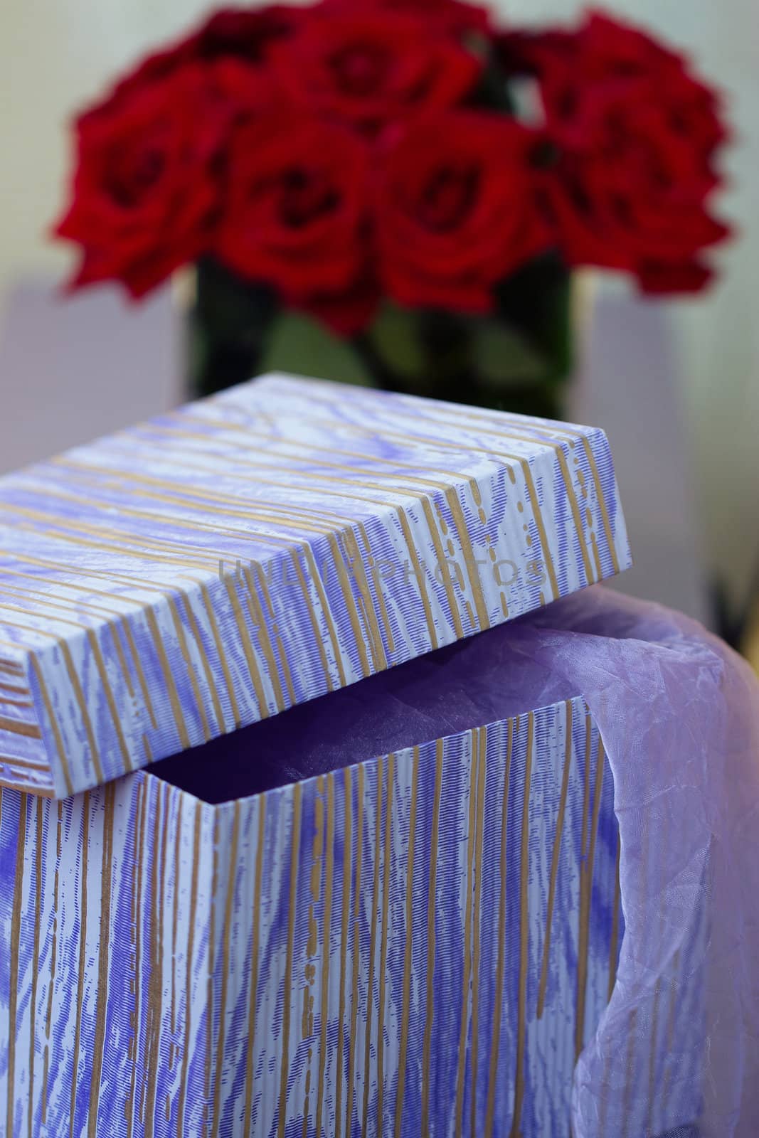 Box with a gift on a background of a bouquet of red roses