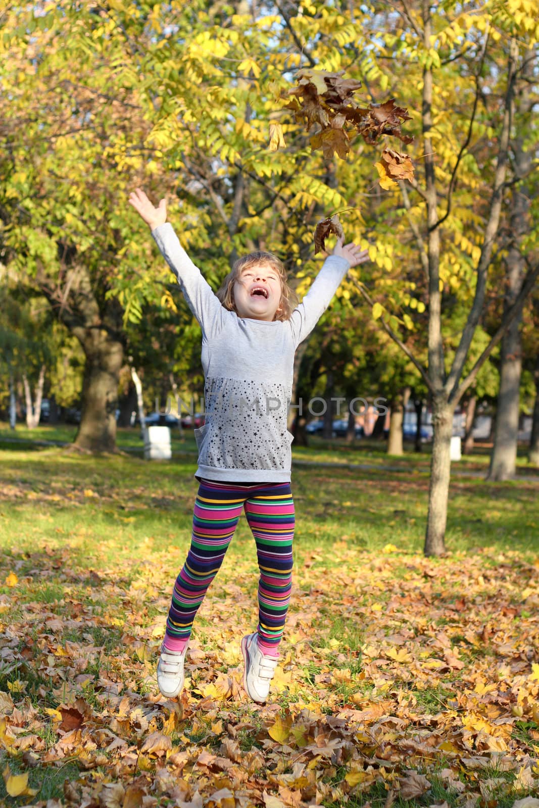 little girl jump and throws leaves by goce