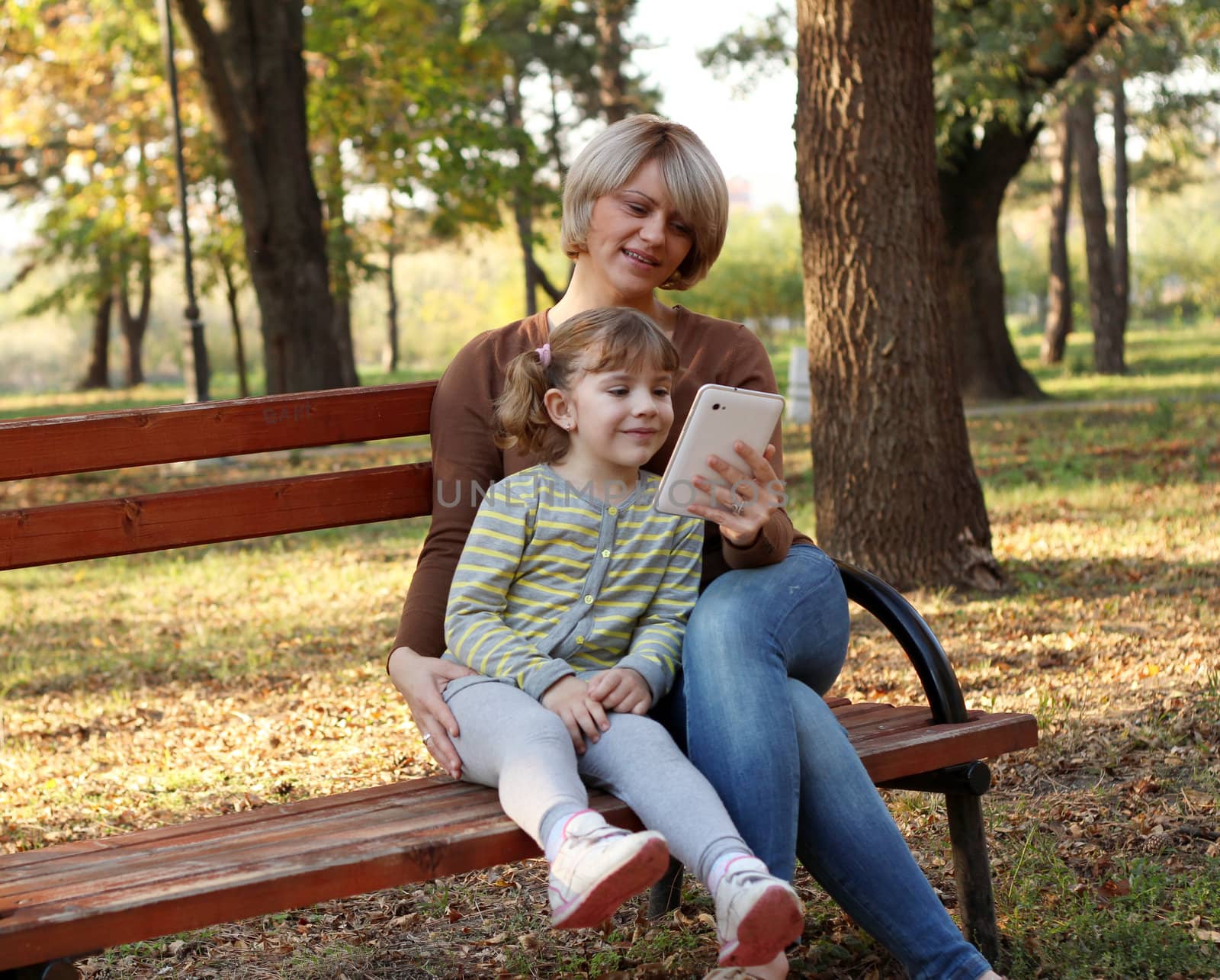 mother and daughter with tablet in park by goce