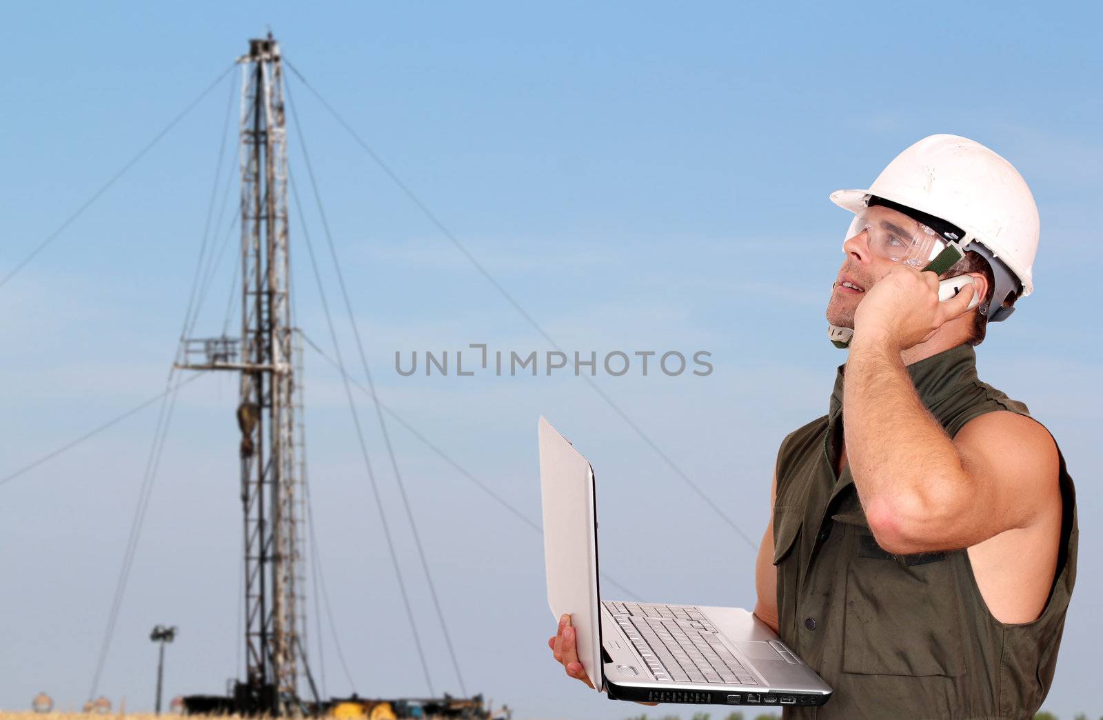 oil worker with laptop and rig