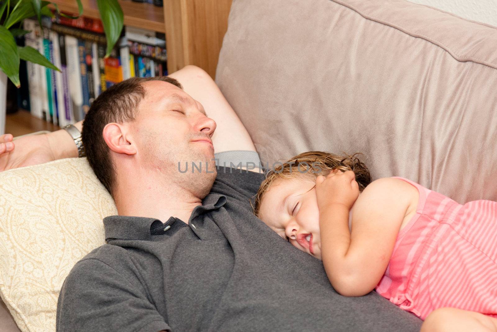 Father and daughter napping on the sofa.