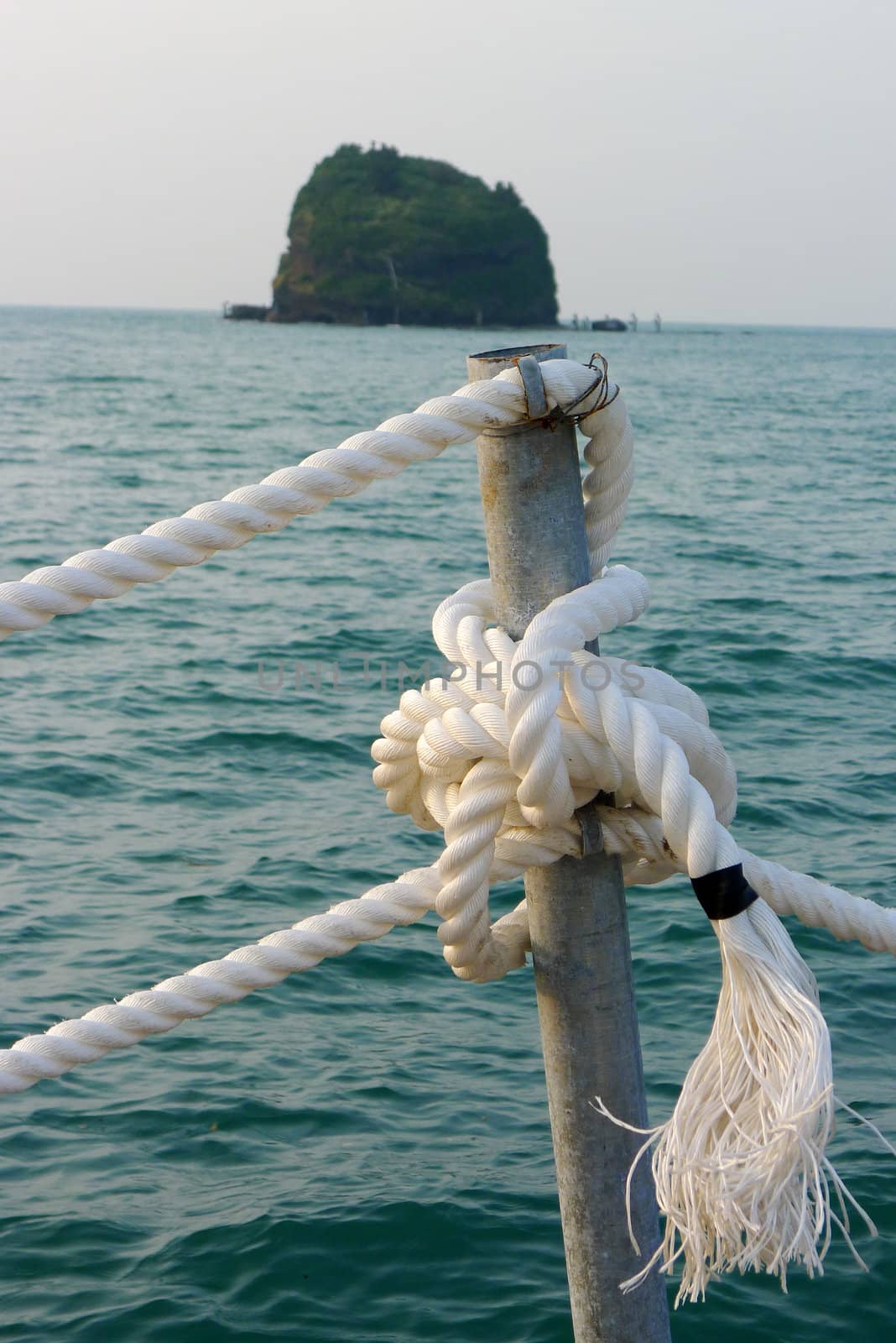 View of ropes on a seaboat with a small island as background