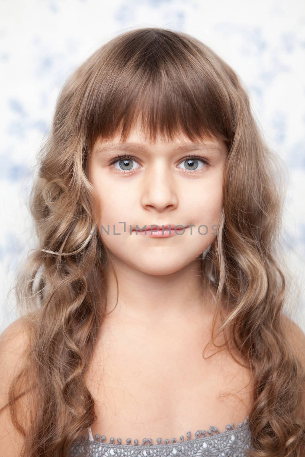 Portrait of sincere cheerful tender young blond girl child with grey eyes and wavy long hair looking at camera