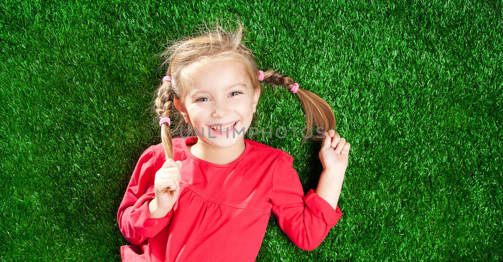 little girl smiling on a green lawn