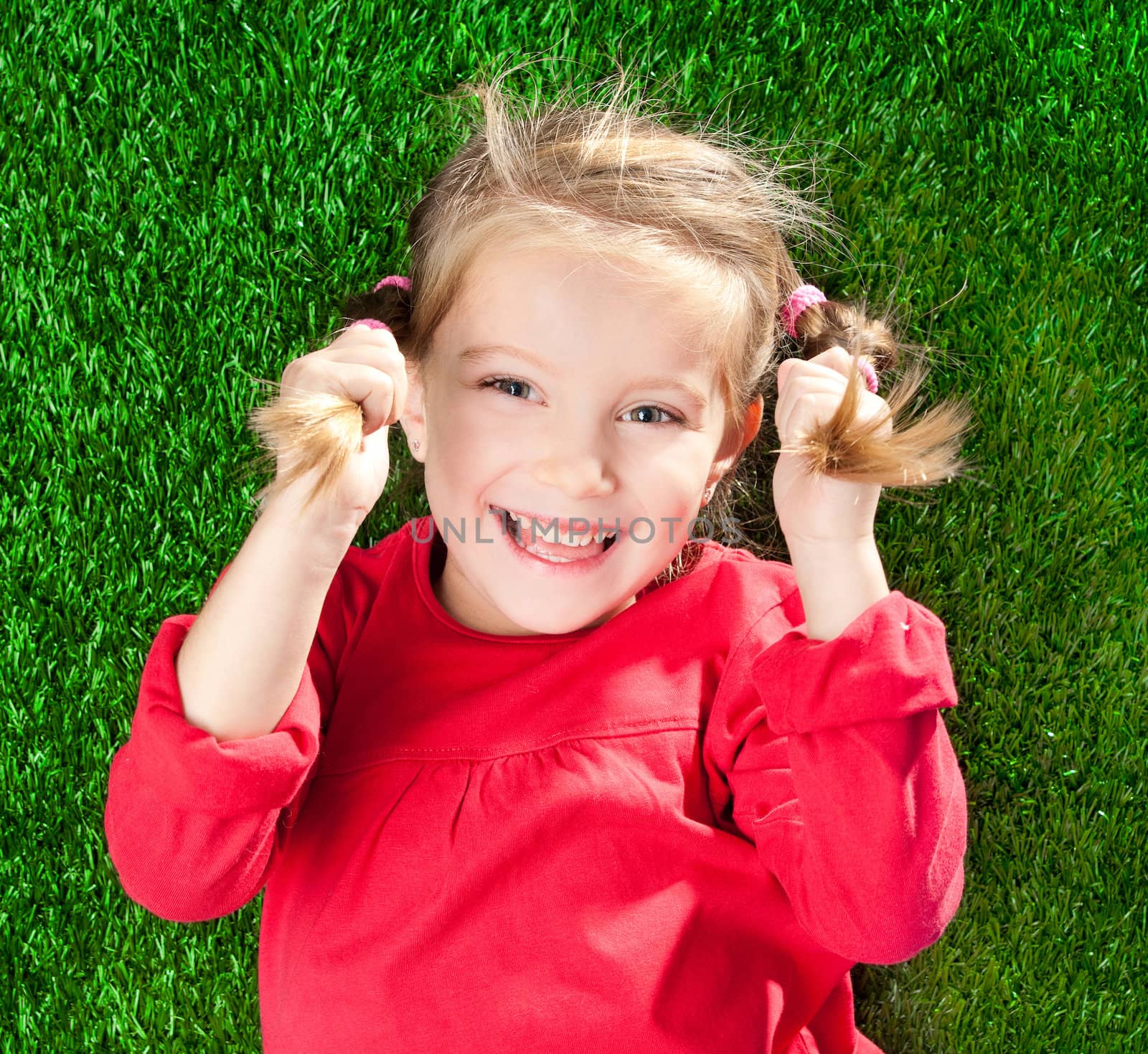 cute little girl smiling on a green lawn