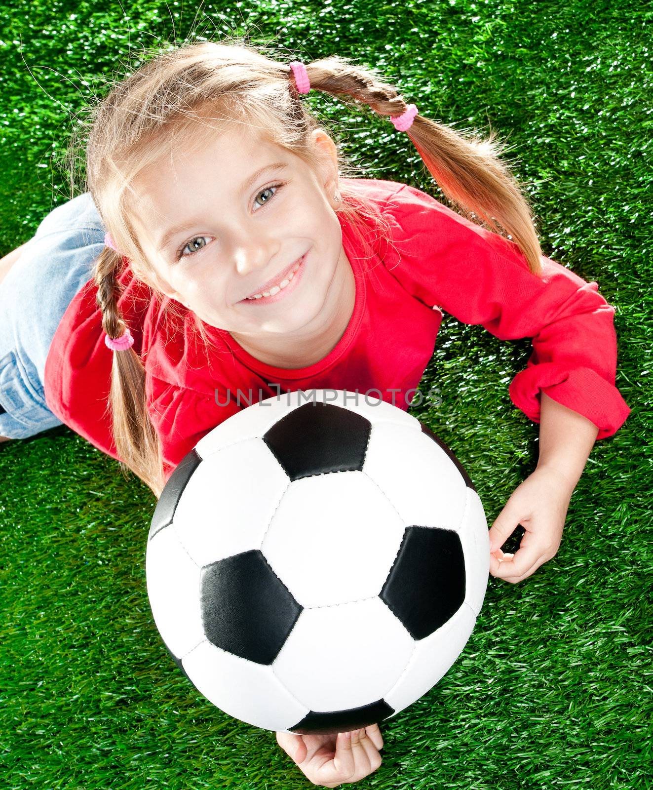 little girl with soccer ball  on a green lawn