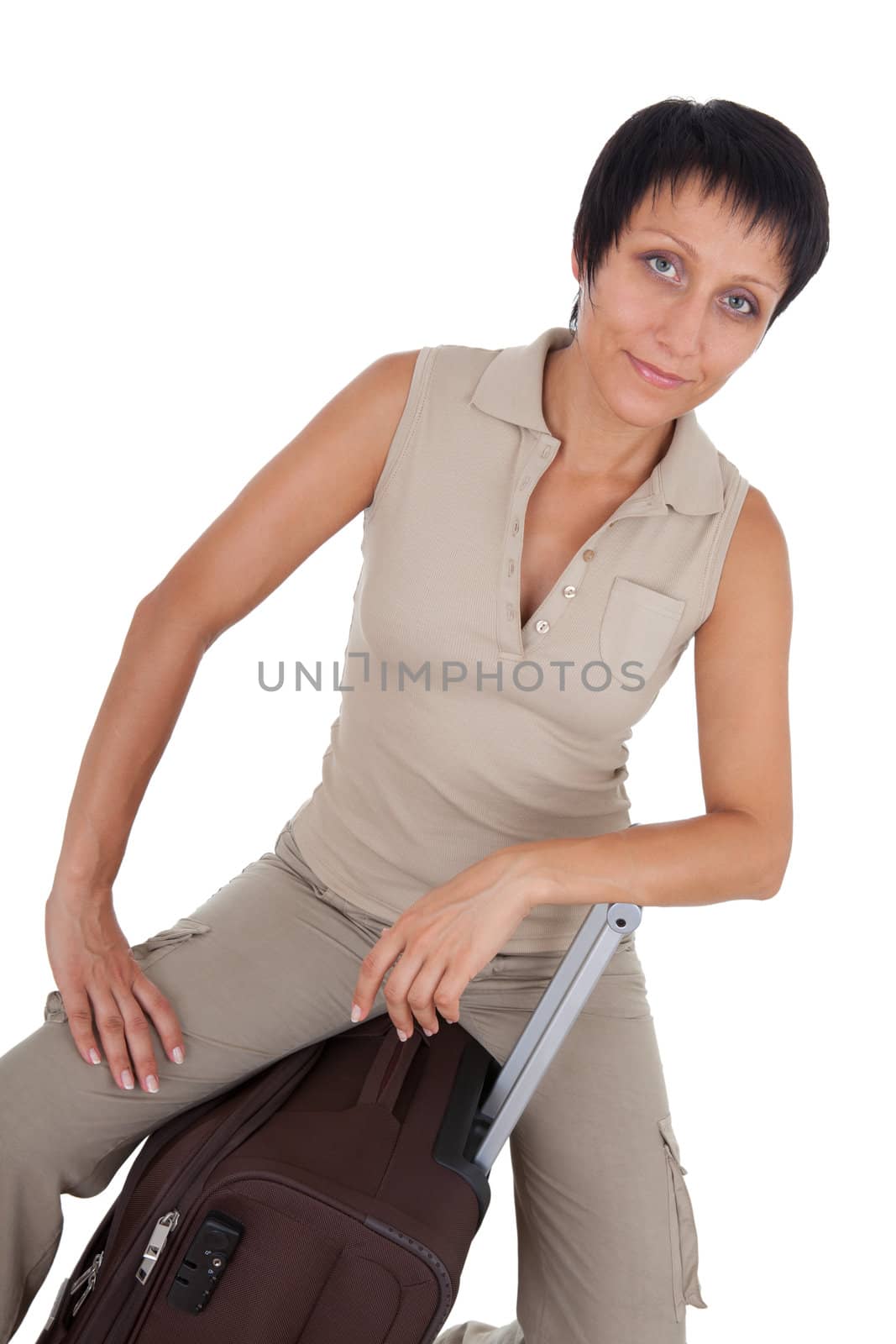 Smiling young tourist haircut woman dressed buff trouser suit sits on the  brown traveling suitcase isolated