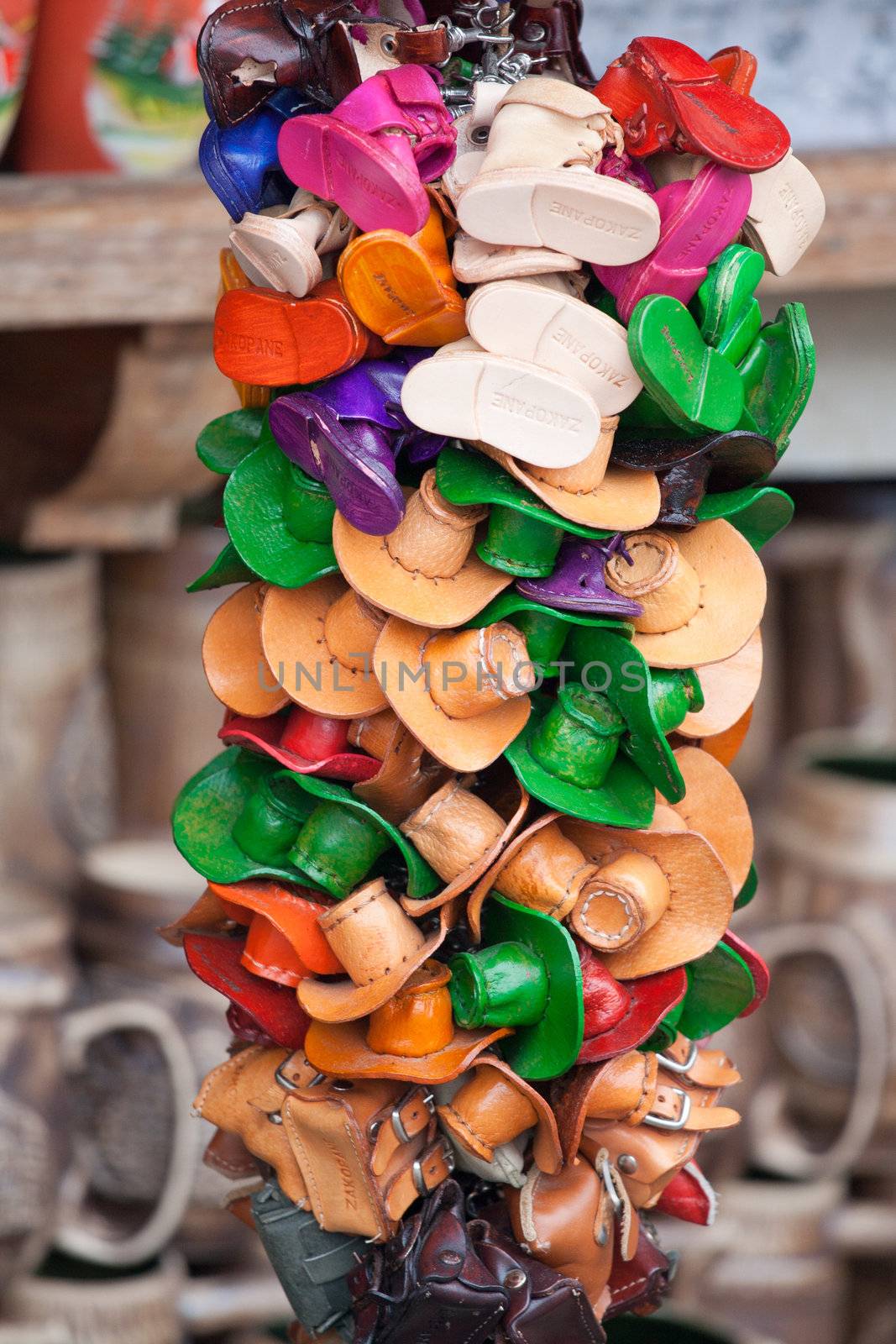 Bundle of small tourists vintage souvenirs multicolored decorative handmade leather hats and boots close-up on craft market in Zakopane Poland