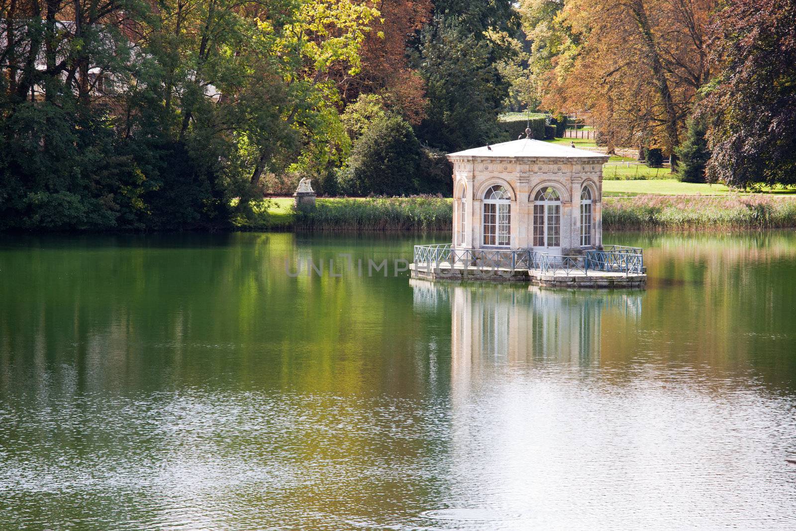 Wonderful Renascence style pavilion on calm pond with trees reflection in many-colored autumn garden