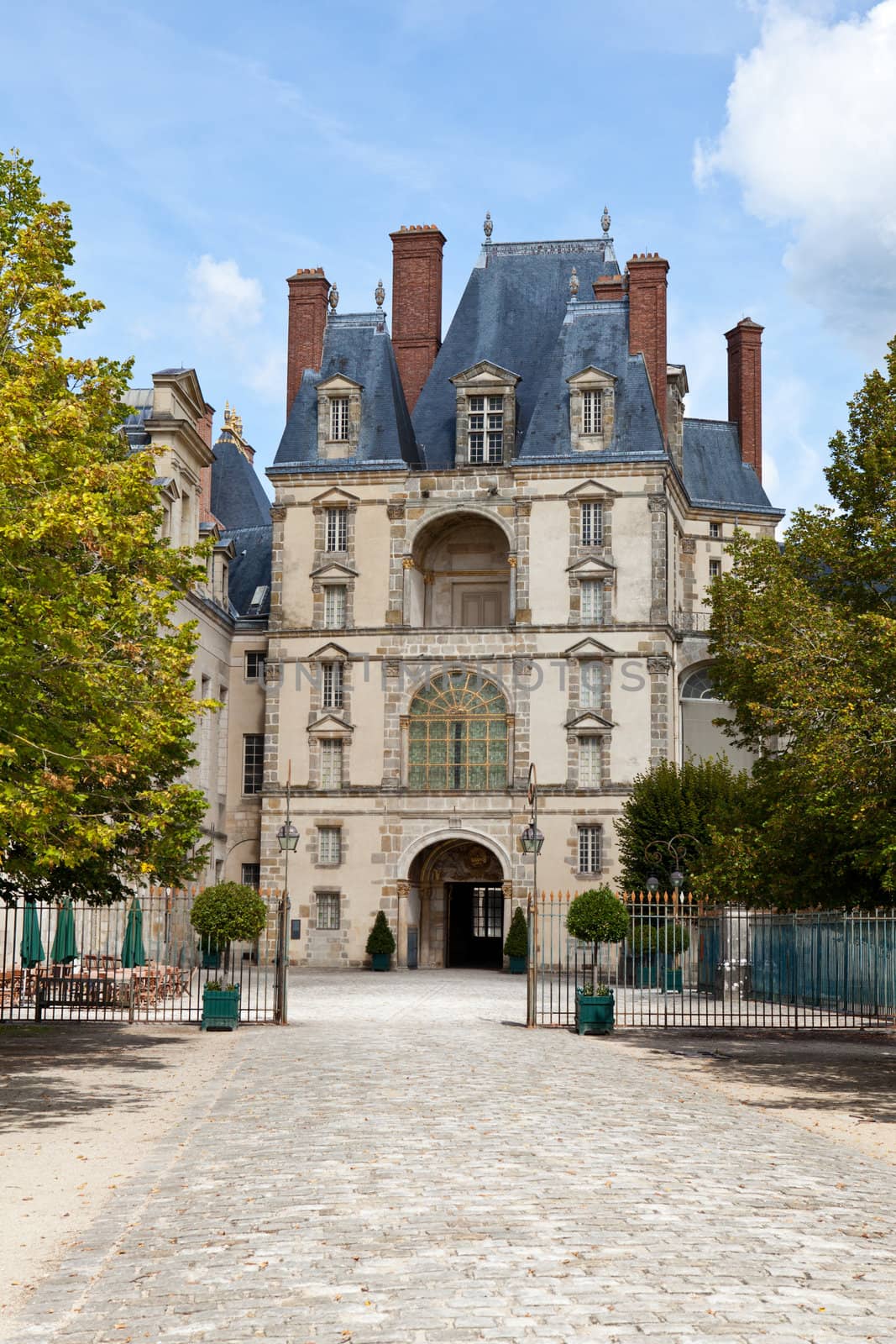 Medieval landmark royal hunting castle Fontainbleau near Paris in France and garden on the cloudy sky background