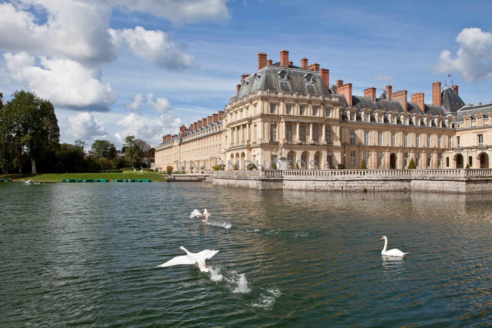Medieval landmark royal hunting castle Fontainbleau near Paris in France and lake with white swans