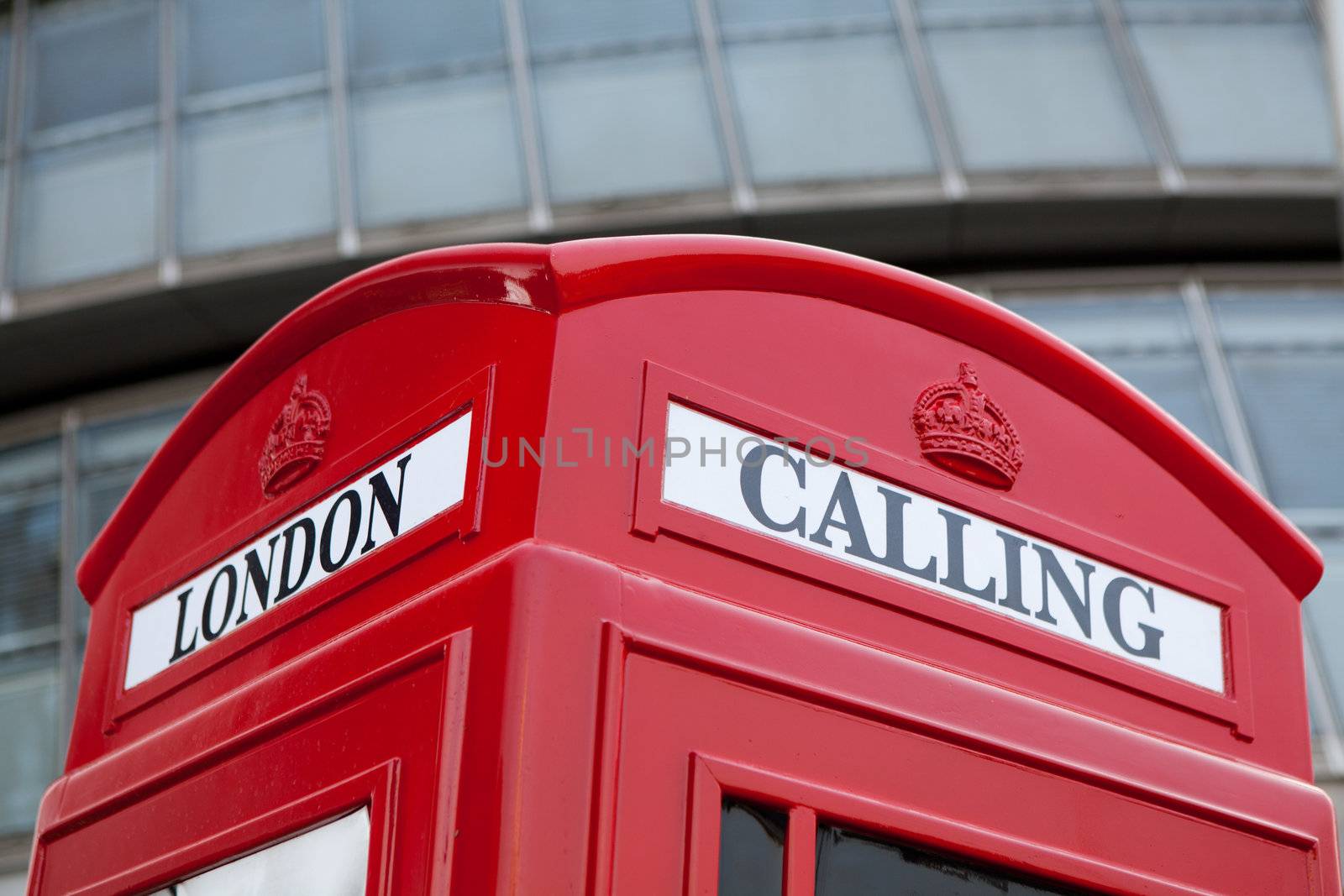 Traditional London symbol red public phone box for calling on the modern business center façade background