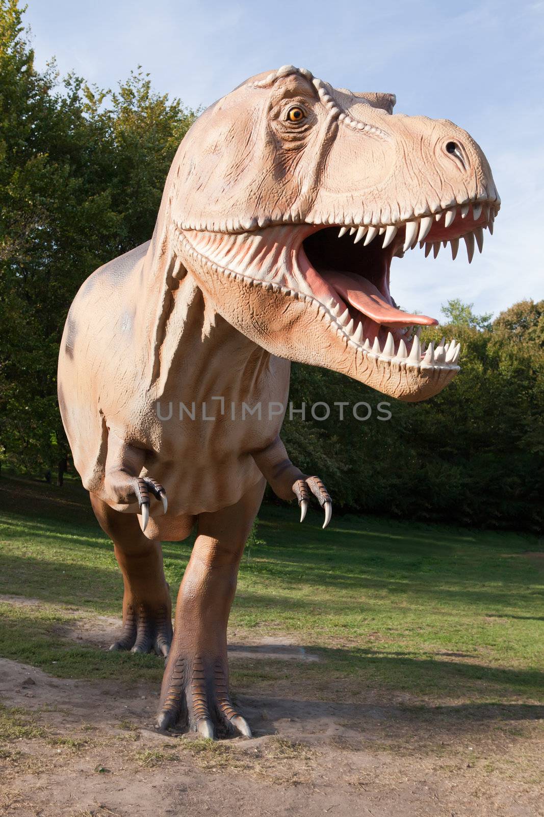 Prehistoric carnivore reptile dinosaur tyrannosaurus rex with open jaw from cretaceous period on green tree and sky background