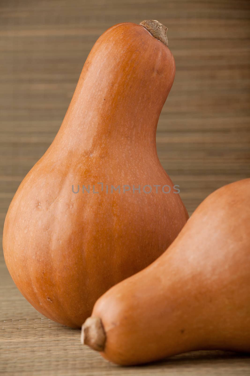 Group of ripe orange gourds on rural straw woven surface and stripy background