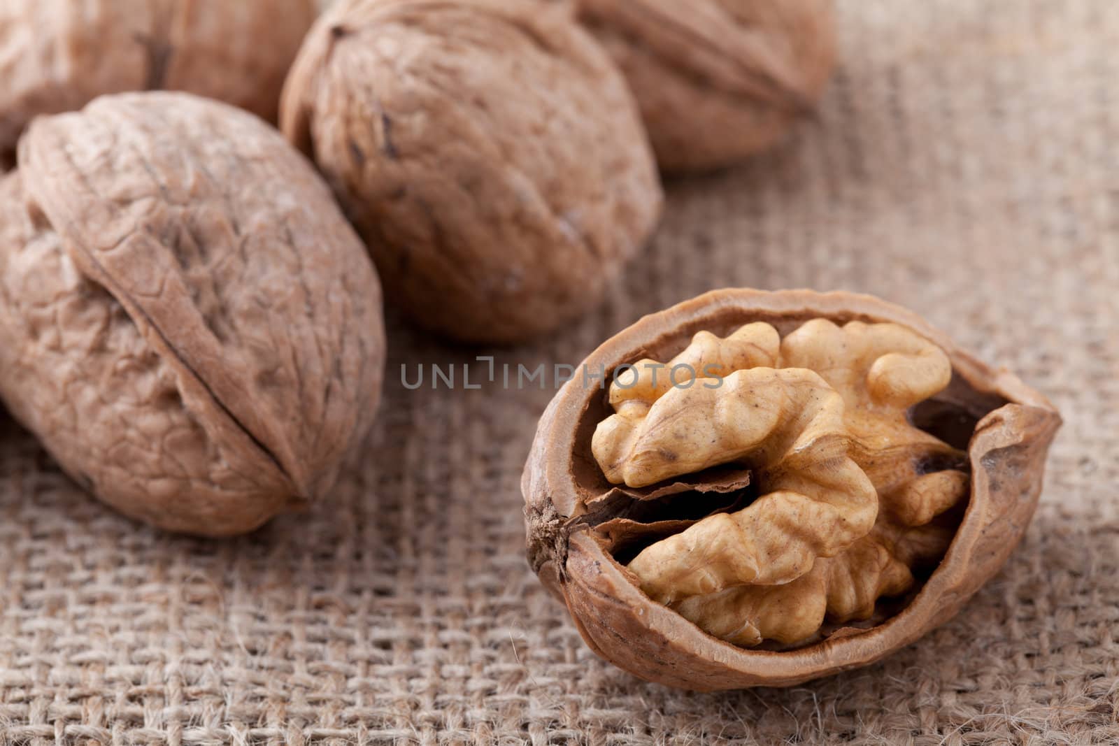 Core of cracked nut close-up, group of brown Circassian walnuts on the sackcloth background