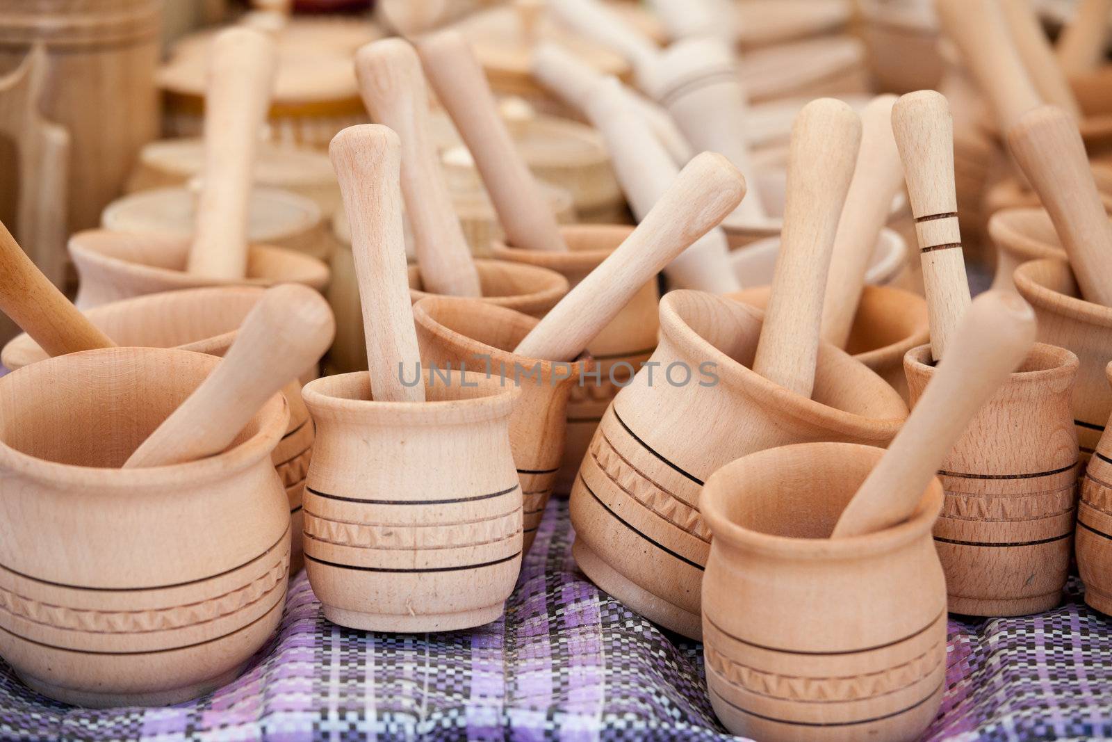 Rustic handmade wooden pounder and pestle on woven towel at street handicraft market