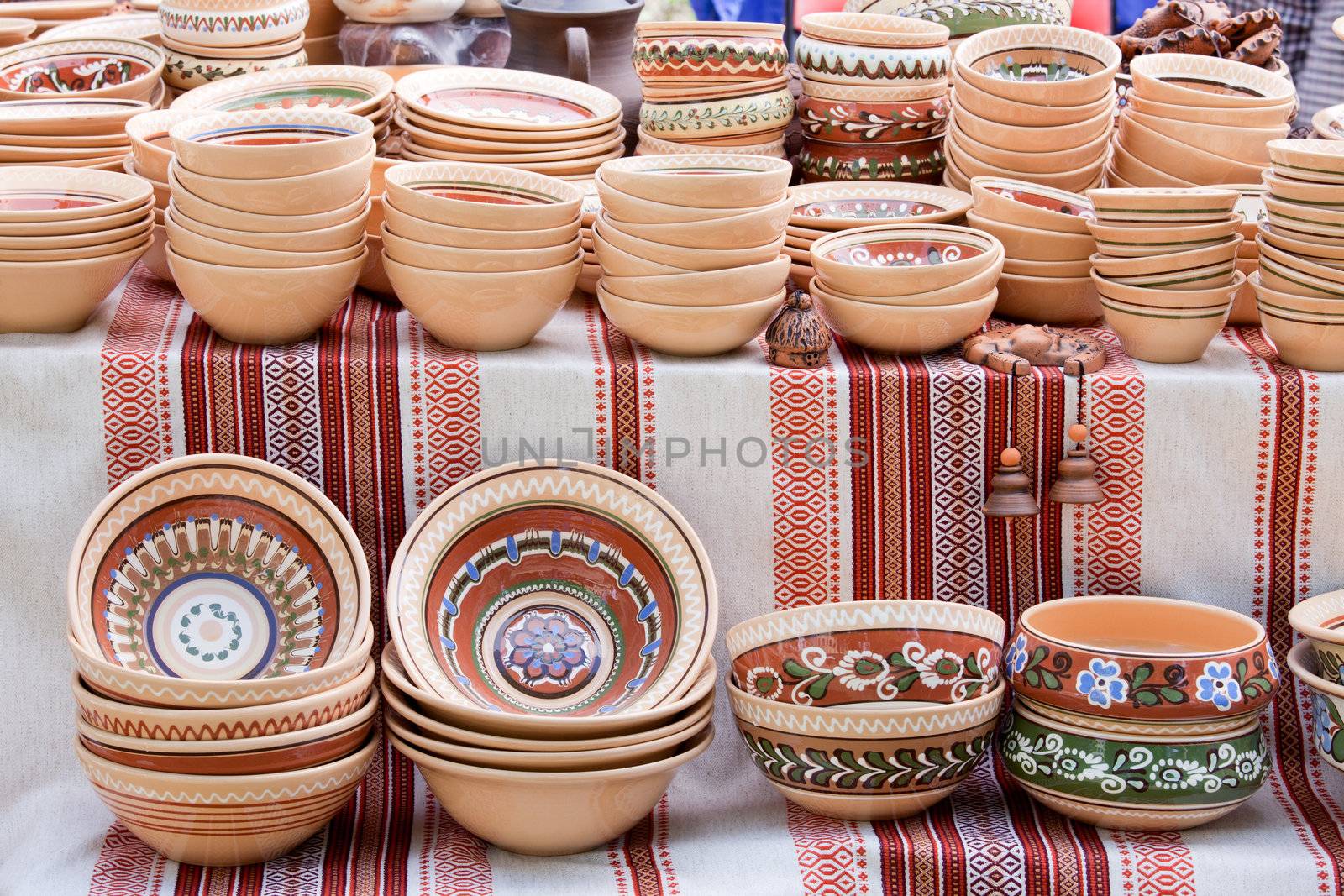 Rustic handmade ceramic clay brown pots souvenirs decorated by traditional ornament, pattern on embroidered Ukrainian towel at street handicraft market