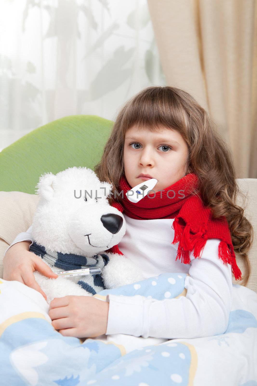 Sympathetic little sick girl with red scarf and clinical thermometer in mouth embraces white toy bear under blanket in the bed