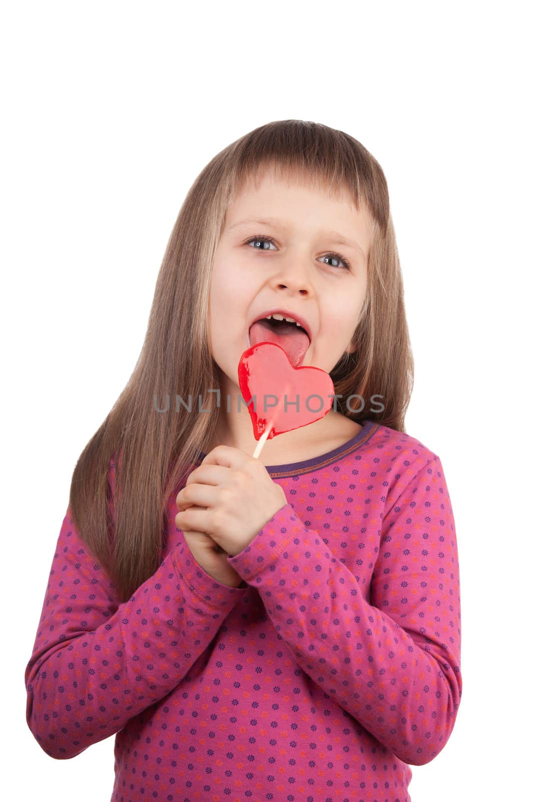 Portrait of little cute happy girl 7-8 years old licking red sweet lollipop in the shape of heart isolated