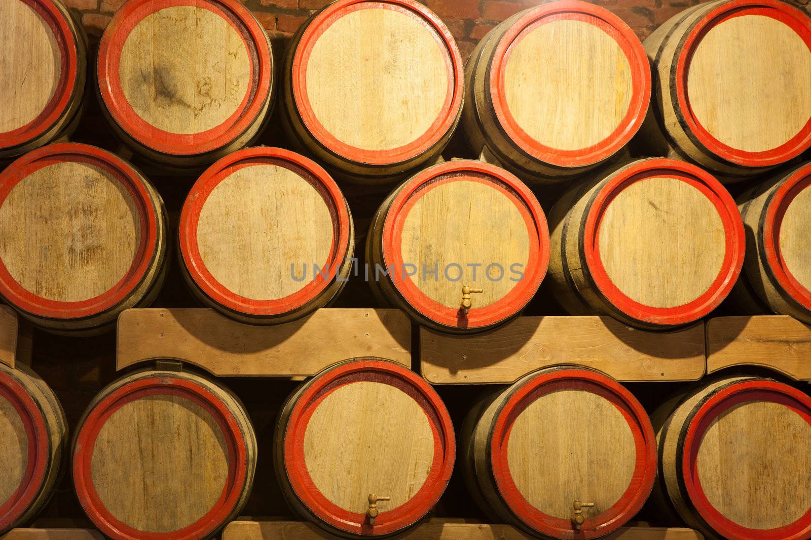 Wooden wine barrels are stored in winery cellar close-up