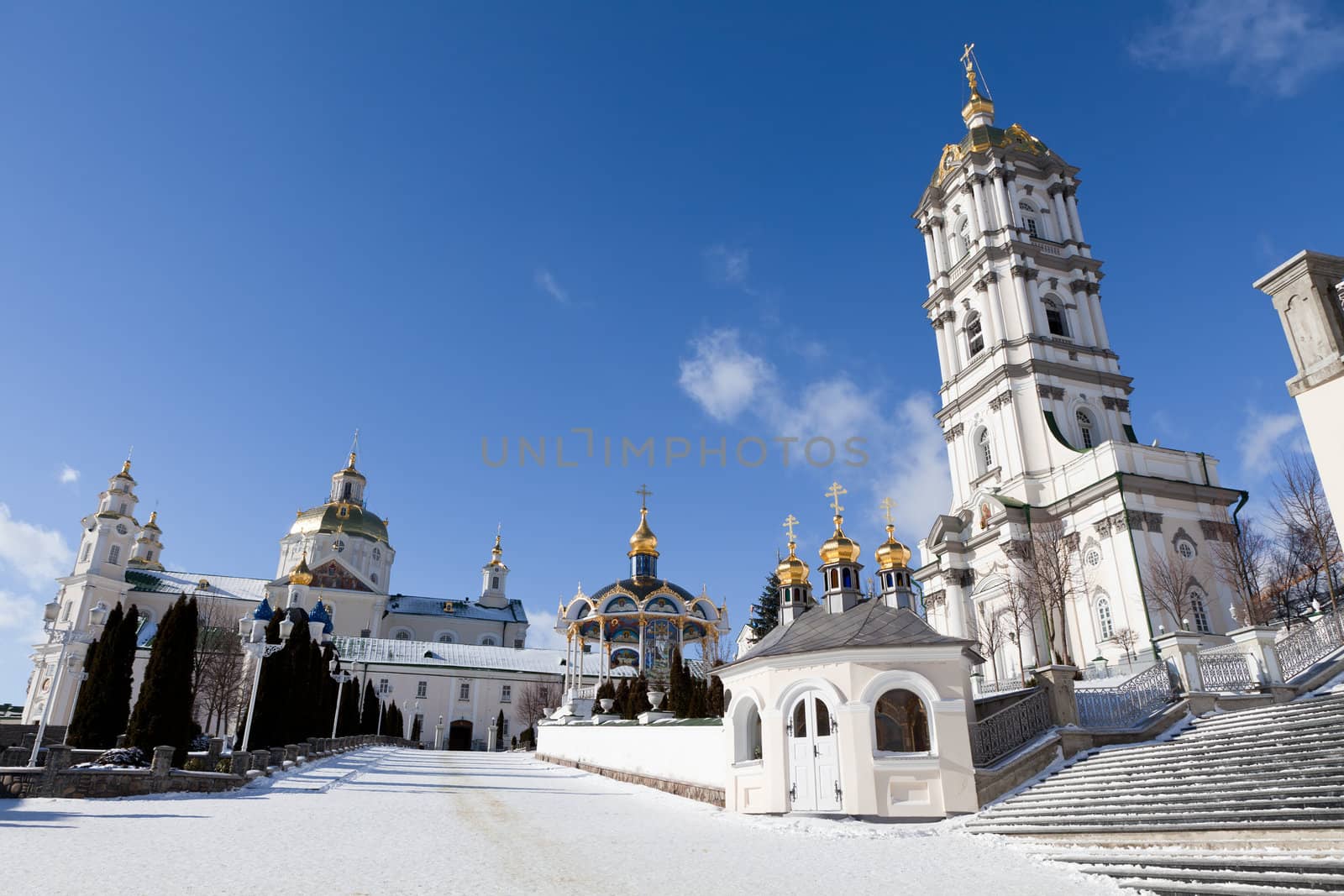 Belfry, dome and church of ancient sacred Christian Pochaev Monastery of Holy Dormition on blue sky background. Western Ukraine, Ternopol region, 16th century