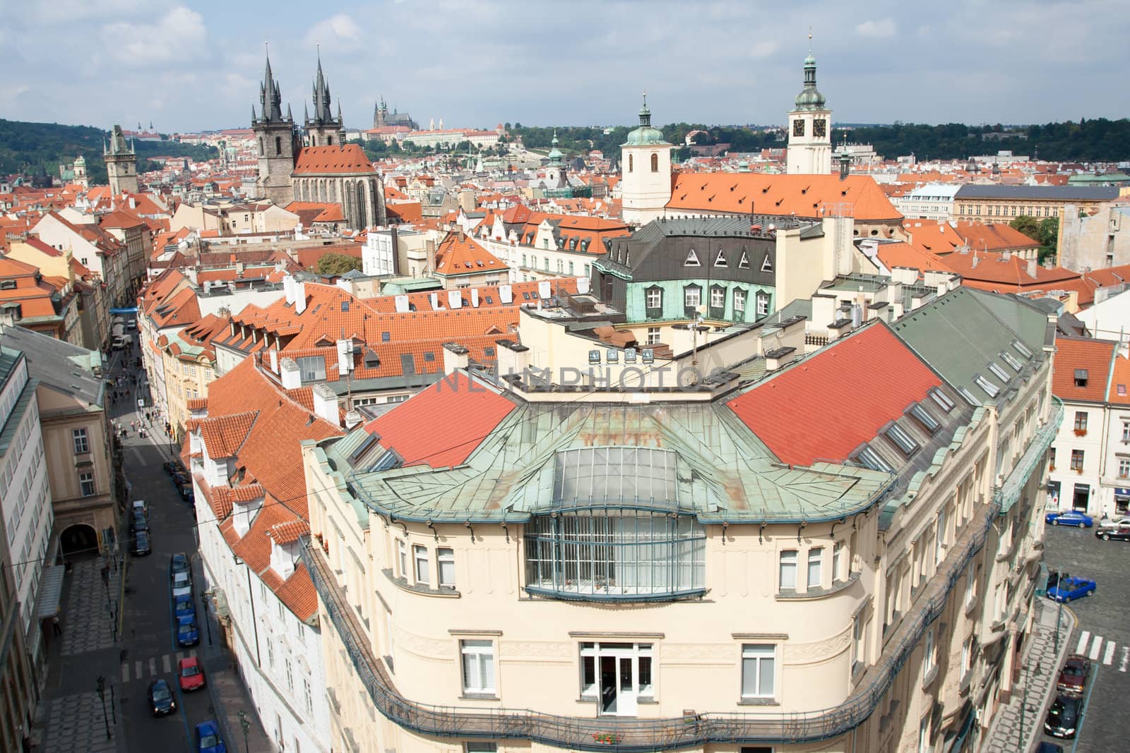 Top view cityscape on facades, red tiled mansard roofs, old Prague streets and district, Gothic cathedrals on blue sky background