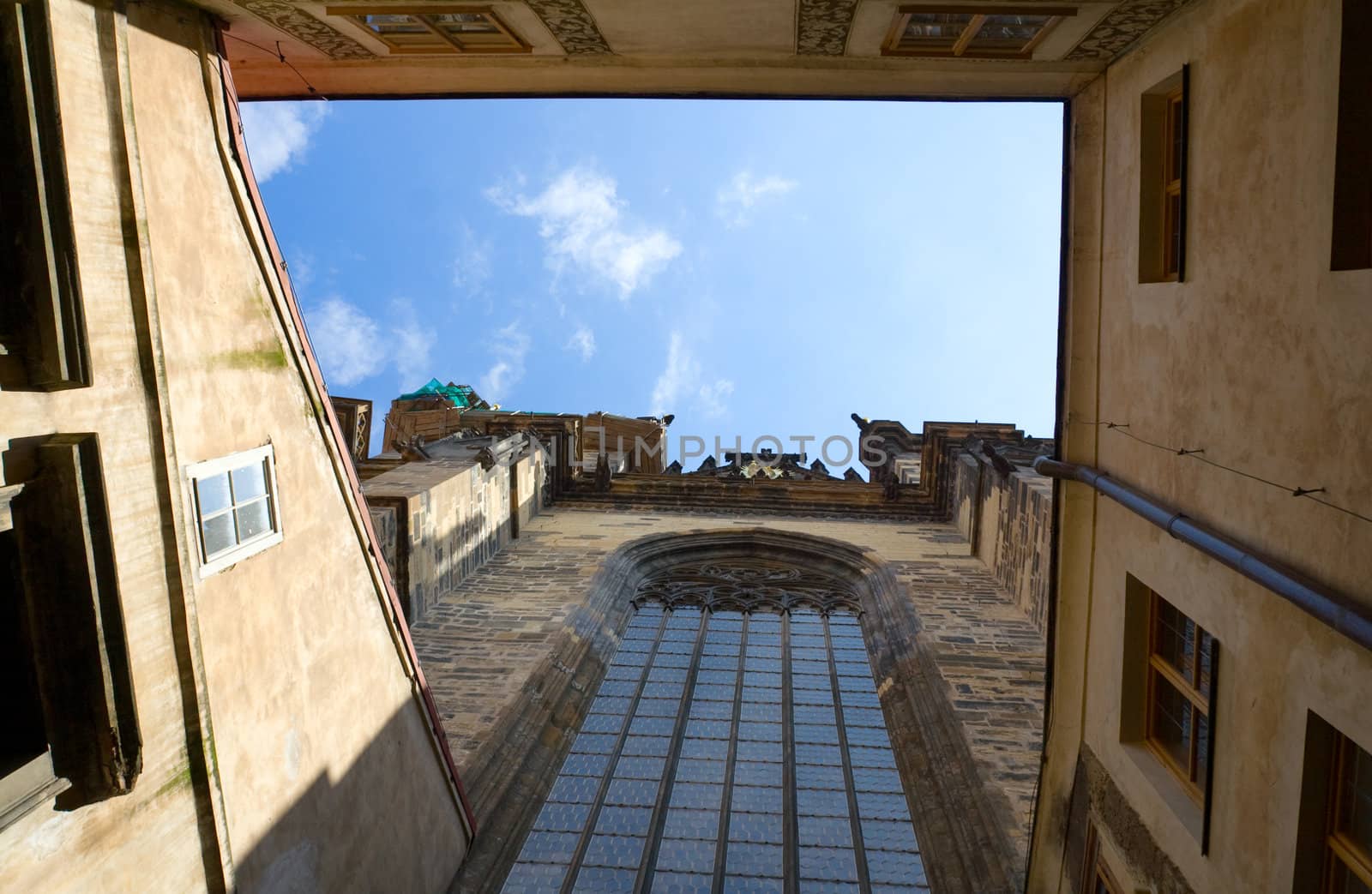 View on blue cloudy sky from inner encloused court of stone catholic gothic church of Virgin Mary Before Tyn with round-headed glass window in Prague Czech Republic