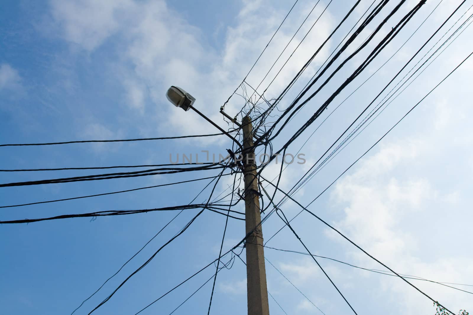 Lamp pole and tangled electric wires on the blue sky background. Horizontal