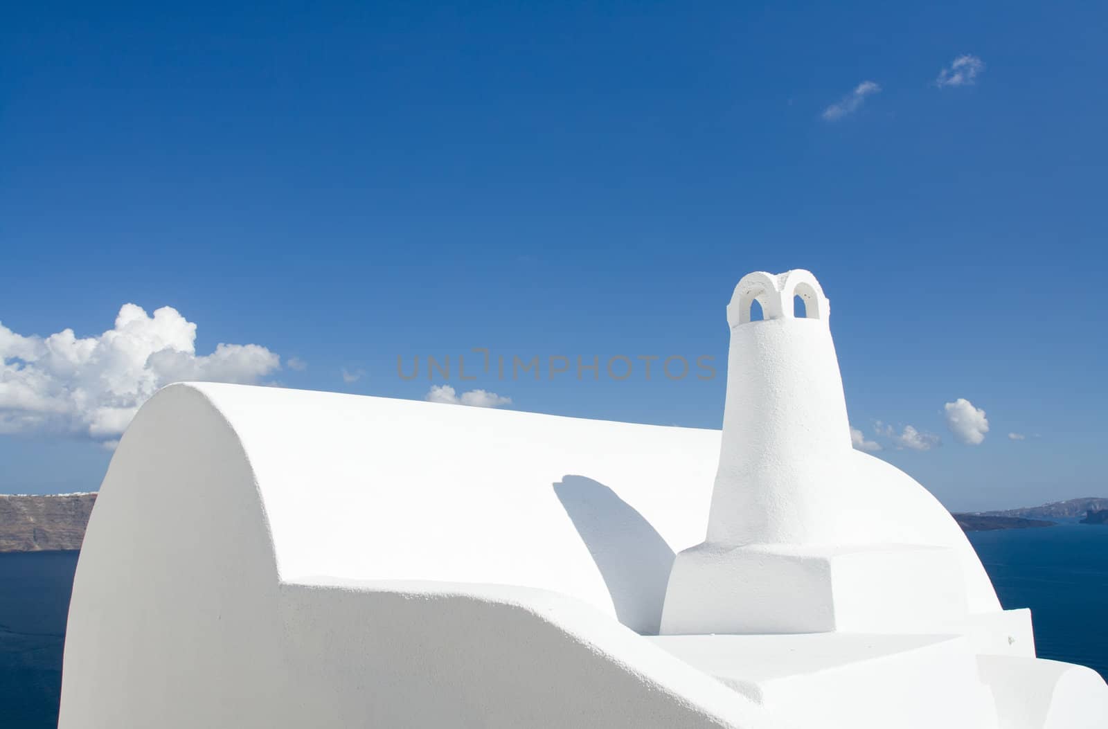 Old-style white traditional Greek roof and chimney in village Oia of Cyclades island Santorini Greece on the blue Aegean Sea and cloudy sky background