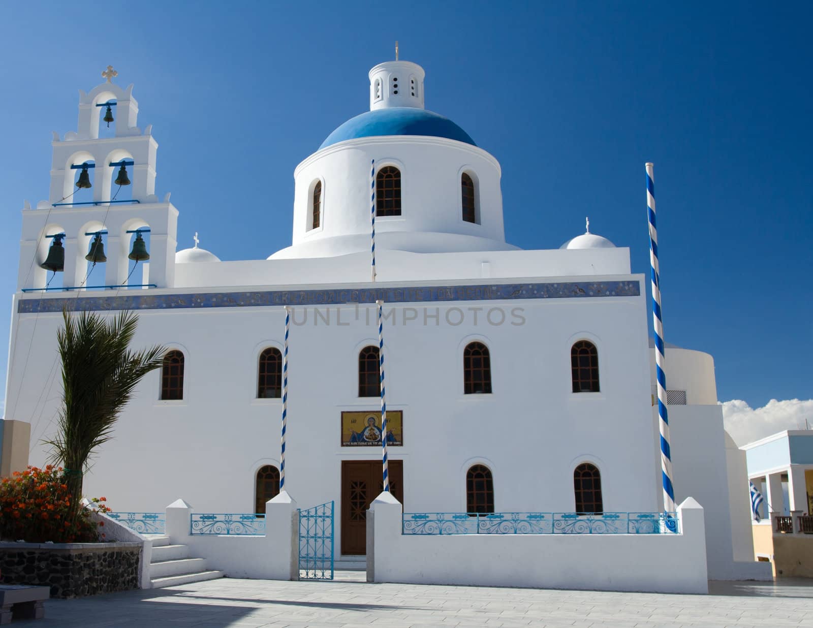 Belfry and cupola of traditional old style white Church of panagia of platsani on Caldera Square in village Oia of Cyclades Island Santorini Greece on the blue sky background