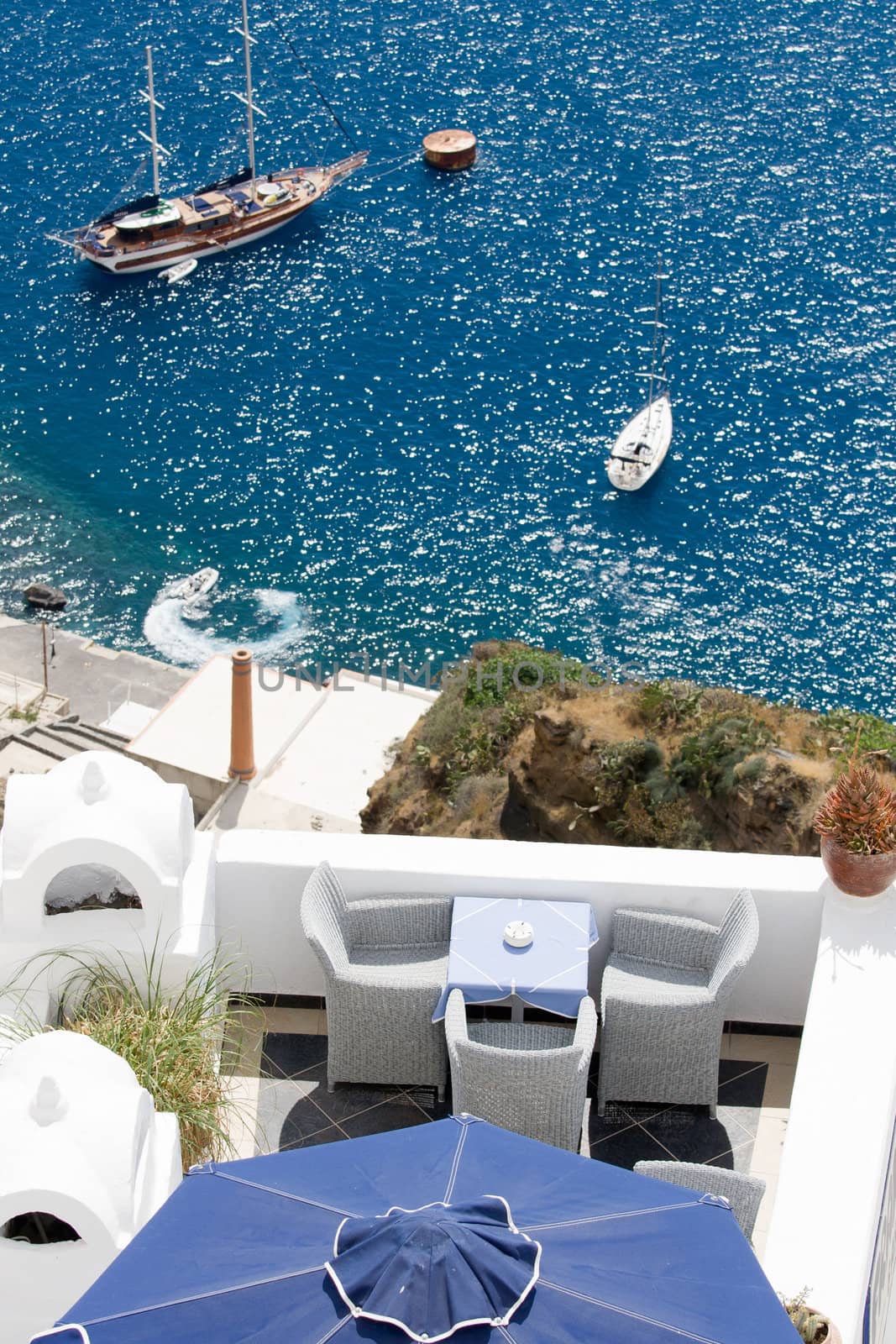 Sea view on moored yacht and sailboat as seen from the restaurant’s terrace on cliff Santorini luxury island, Greece