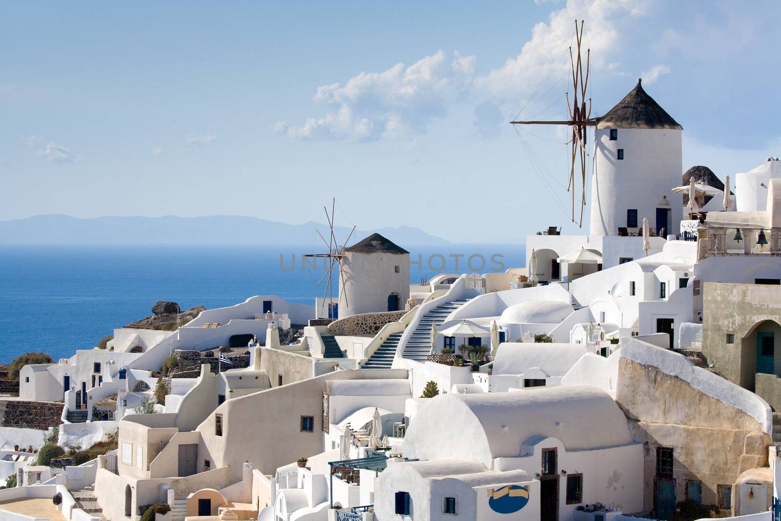 Old-style white traditional windmills in terraced village Oia of Cyclades island Santorini Greece on the blue Aegean Sea and sky background