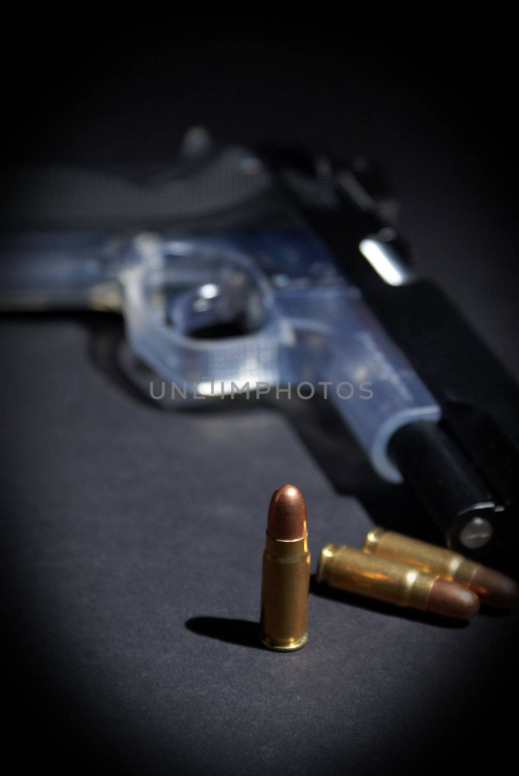 A handgun and selective focus on the upright bullet.