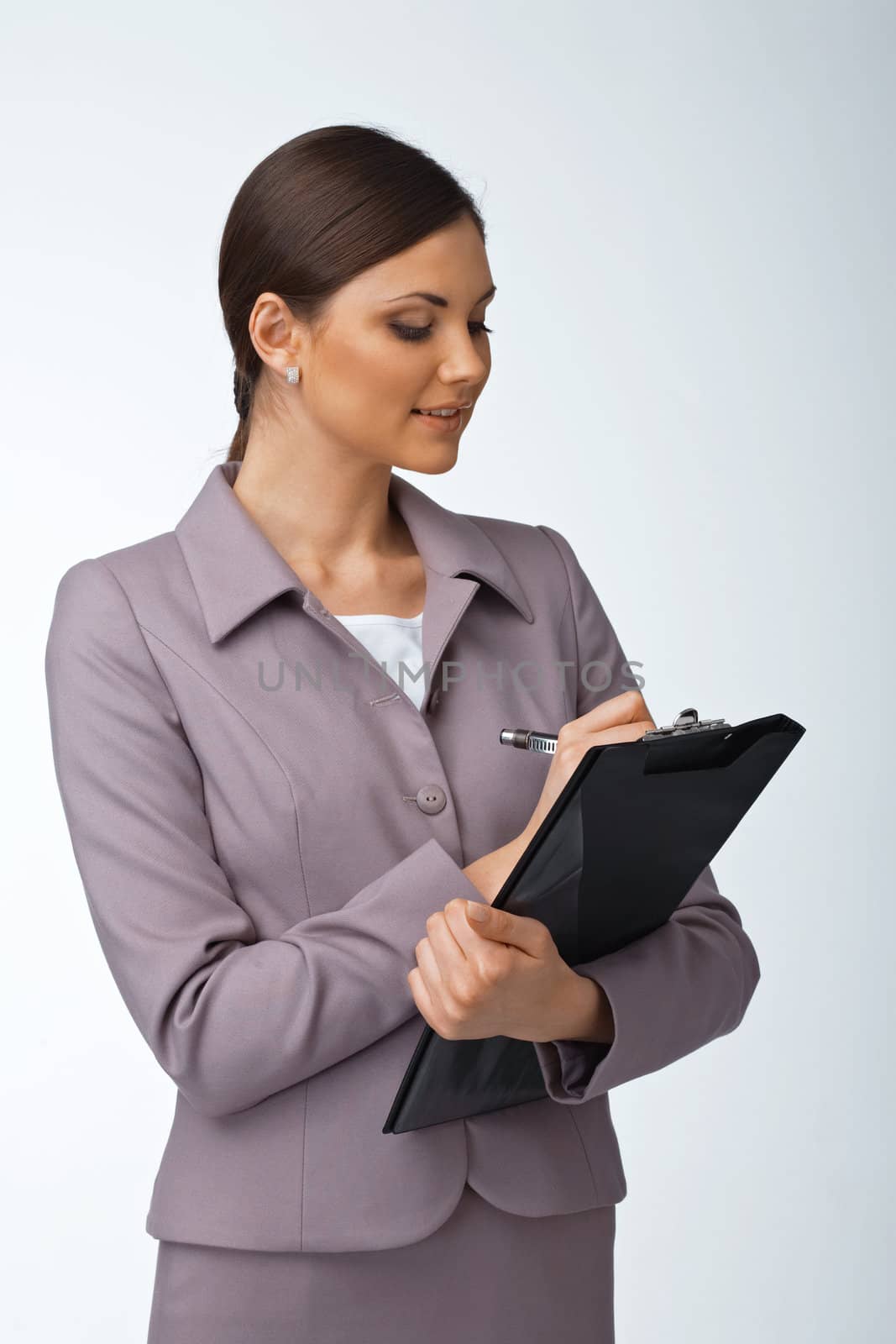 Portrait of a young business woman writing something on the folder with papers