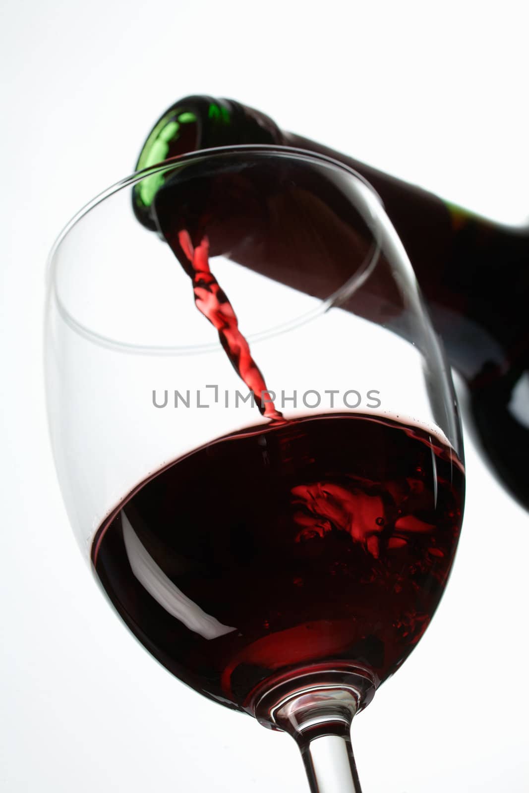 Red wine pour in a glass on white background