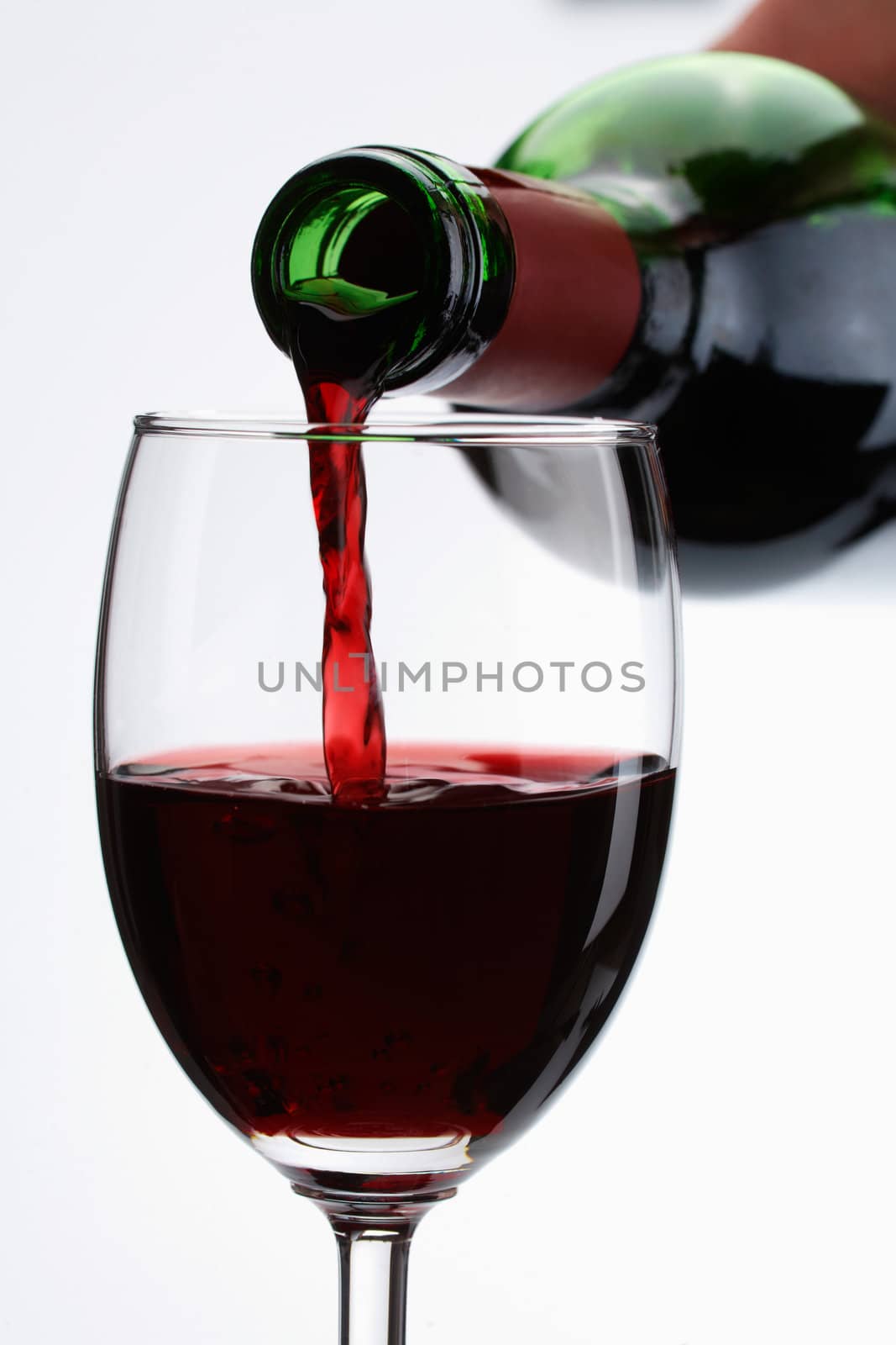 Red wine pour in a glass on white background