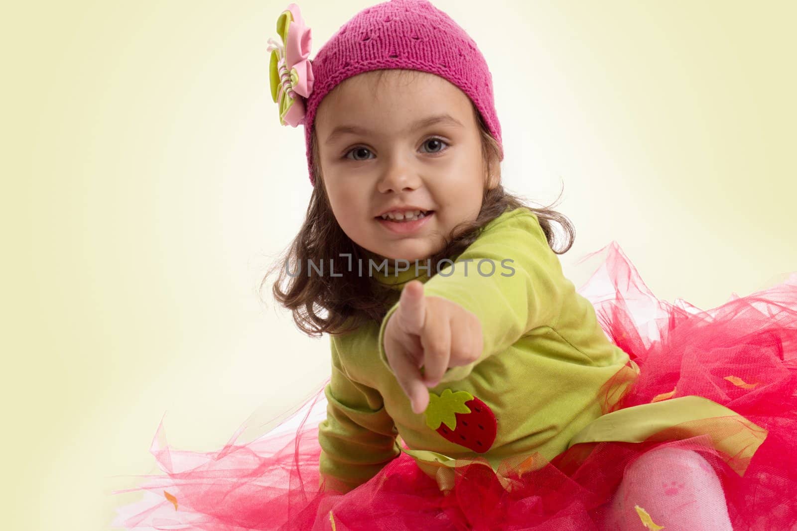 Adorable girl in tutu and hat with butterfly pointing over green back
