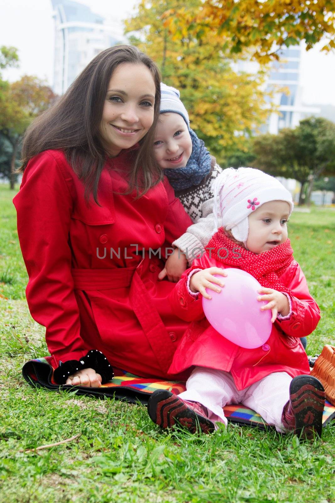 Mother and two lovely children sitting in autumn park 
