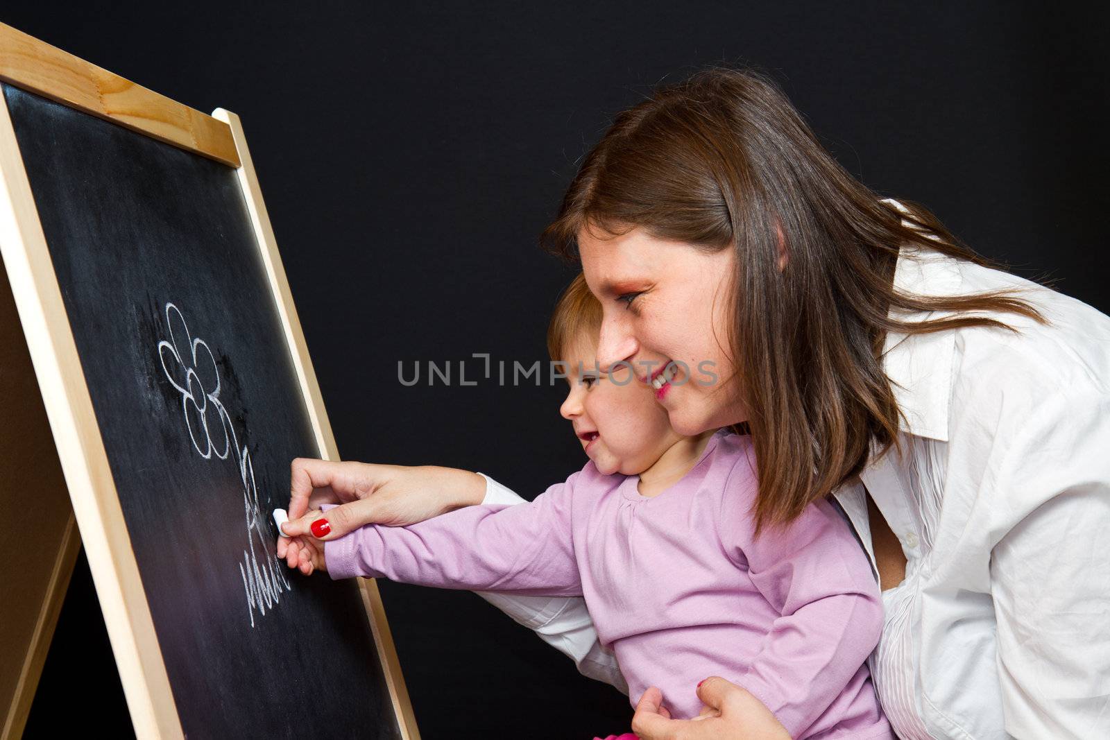 Mother and little daughter writing on a blackboard