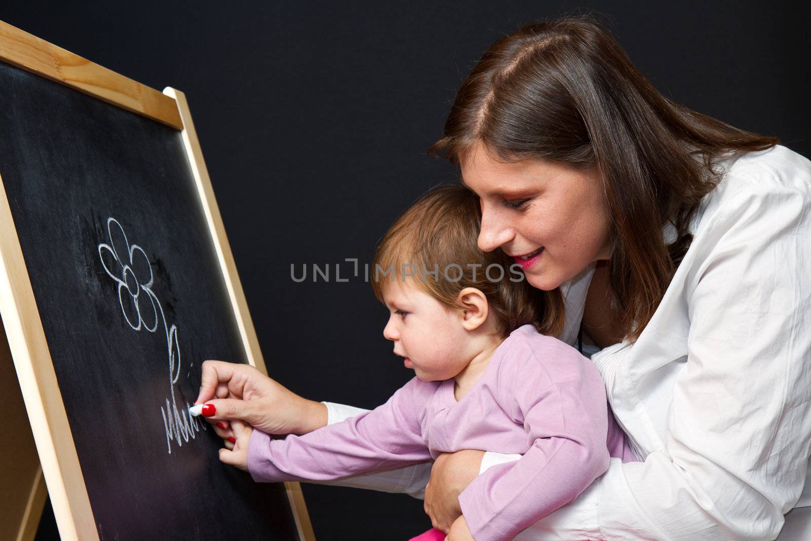 Mother and little daughter writing on a blackboard by lsantilli