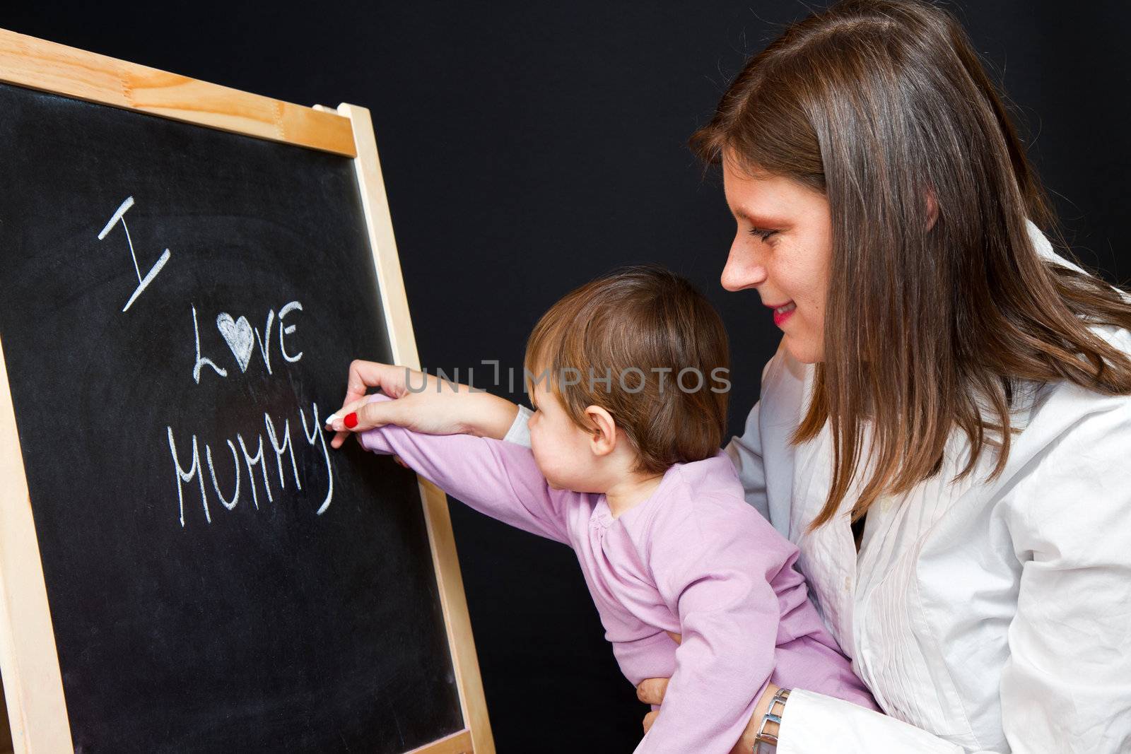 Mother and little daughter writing on a blackboard by lsantilli